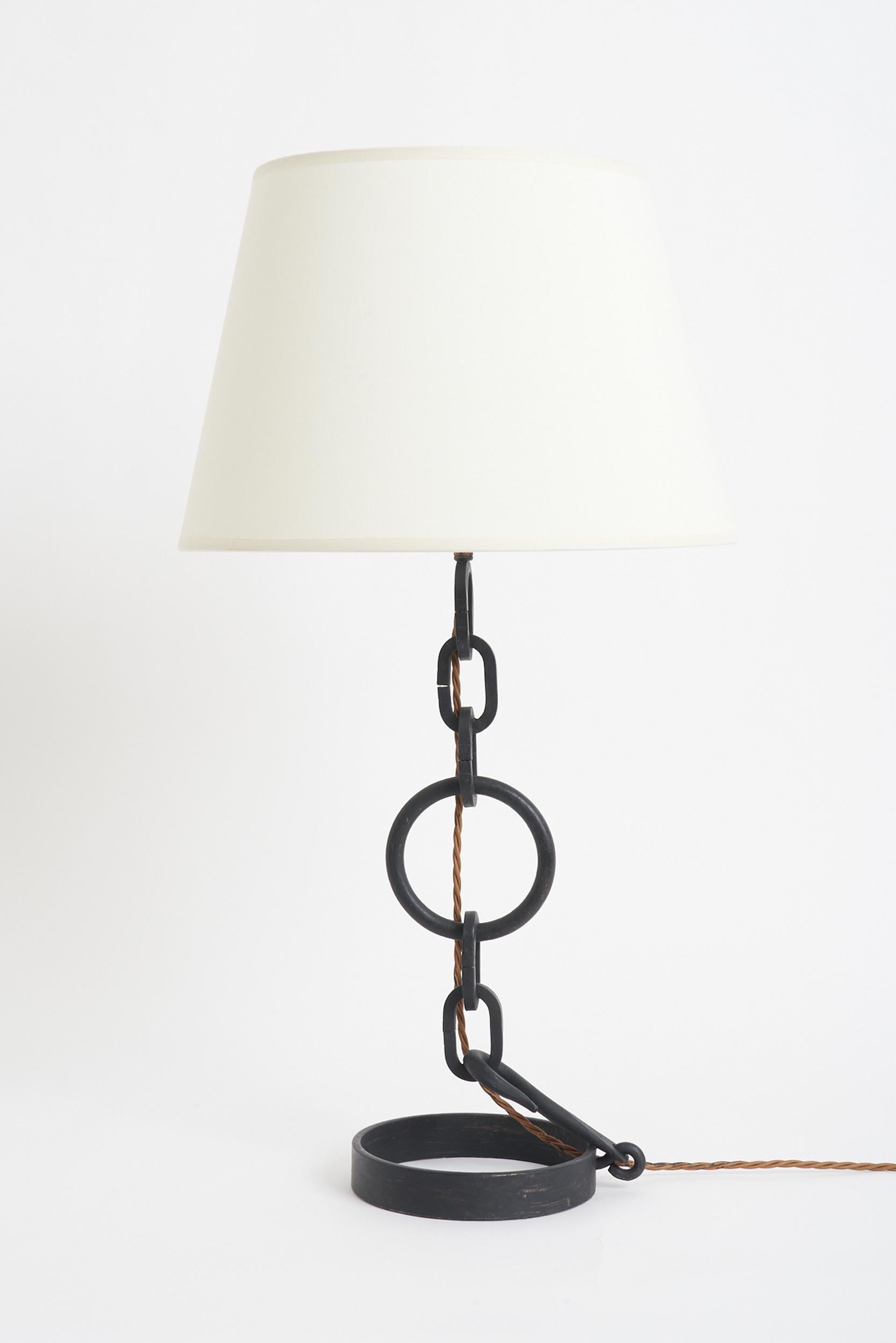 Une lampe de table en maillon de chaîne patiné noir.
France, milieu du 20e siècle. 
Avec l'abat-jour : 68 cm de haut par 36 cm de diamètre 
Base de la lampe uniquement : 48 cm de haut par 16 cm de diamètre