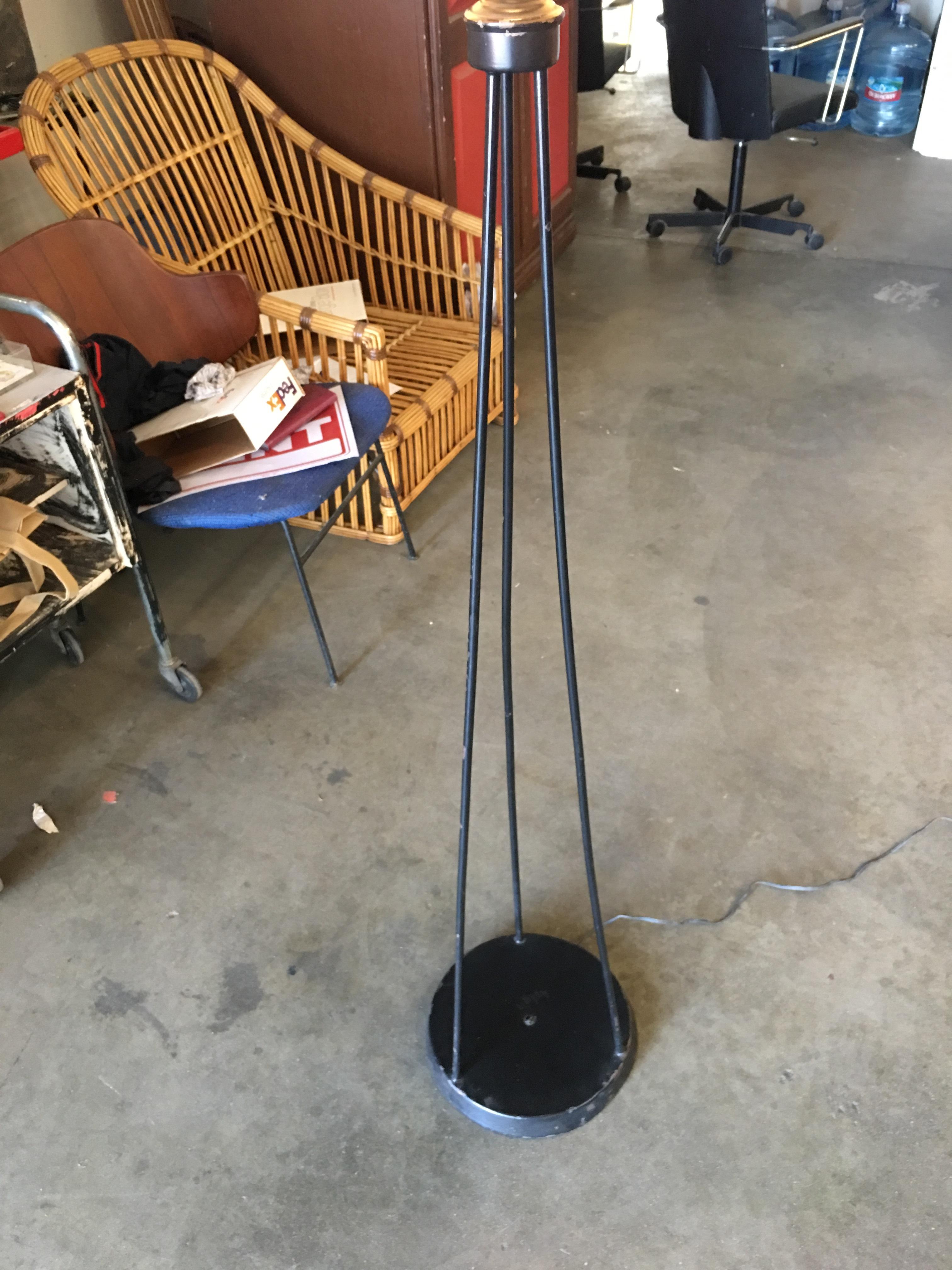 Midcentury black iron rod tripod floor lamp with round base and oversized white lamp shade.