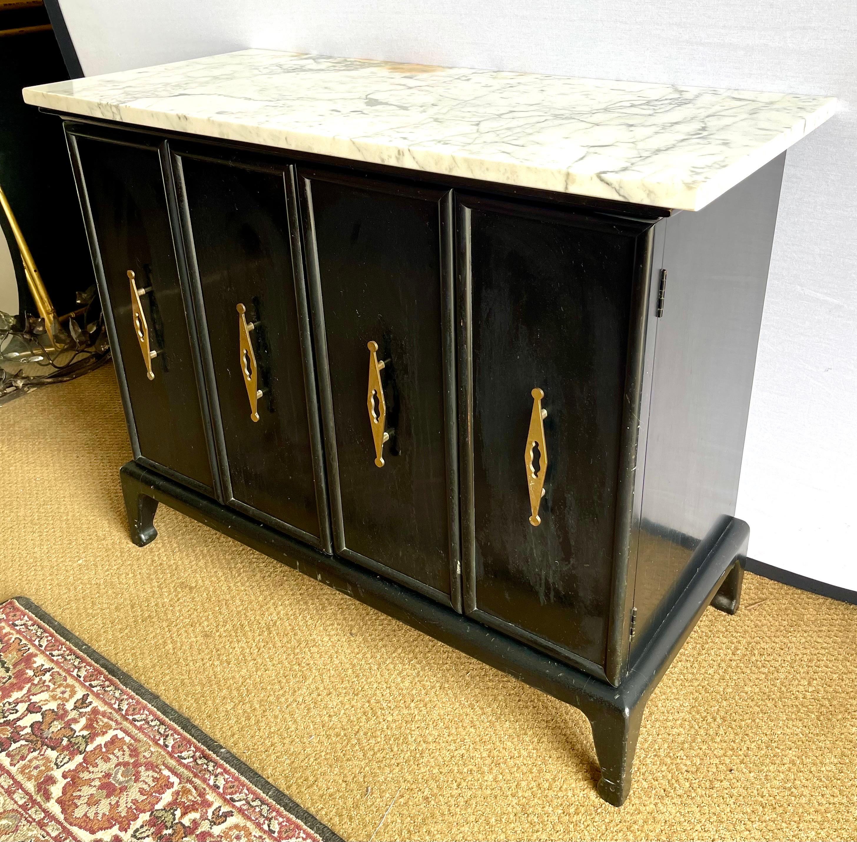 Mid century black lacquer cabinet with marble top has two front doors with sculptural brass diamond pulls. Use as a buffet, sideboard or bar to store your liquor. Good condition but does has stain on top a marble in one section which is detailed in
