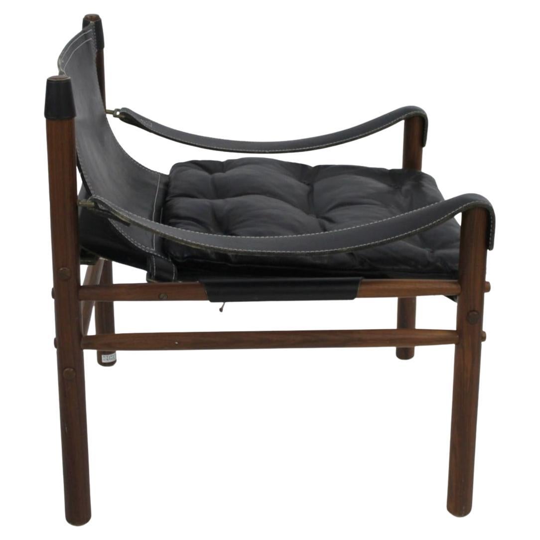 Sillón moderno sueco Sirocco safari, de Arne Norell. Precioso asiento blando de cuero negro con herrajes de latón. Tiene una robusta estructura de madera dura de palisandro oscuro con asientos de cuero negro tejido. Buen estado vintage teniendo en