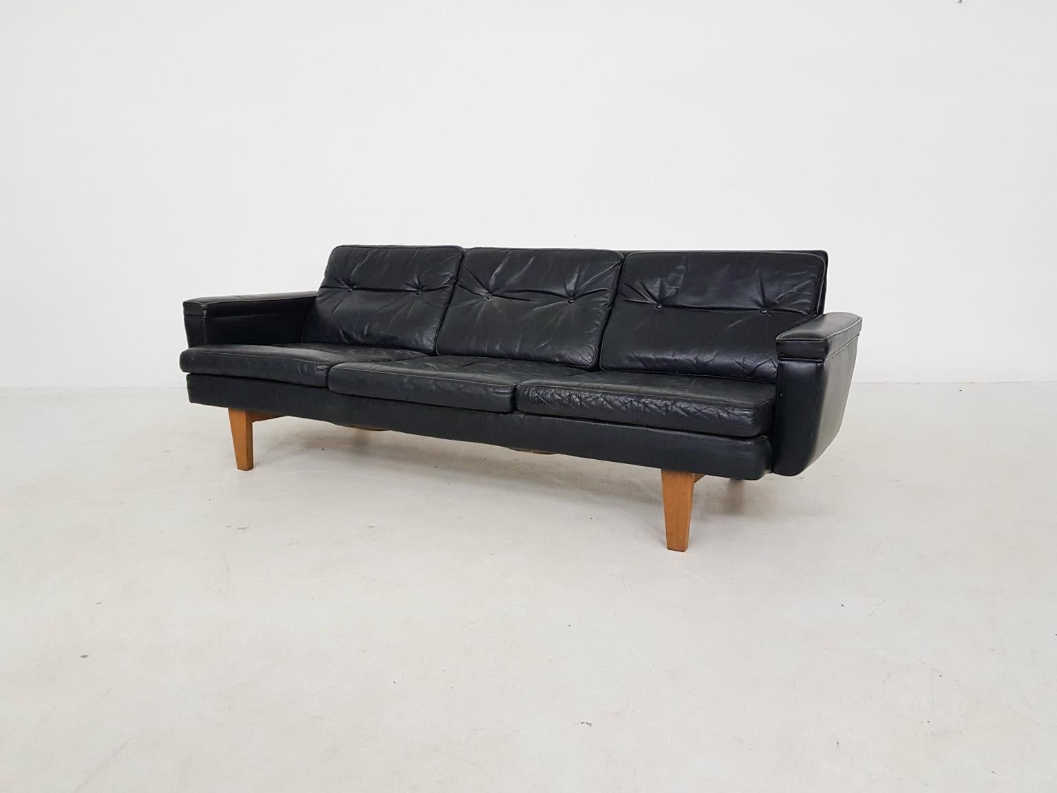 Very nice black leather vintage design sofa on wooden feet.

A repair to the right arm rest.

Marked at the bottom.