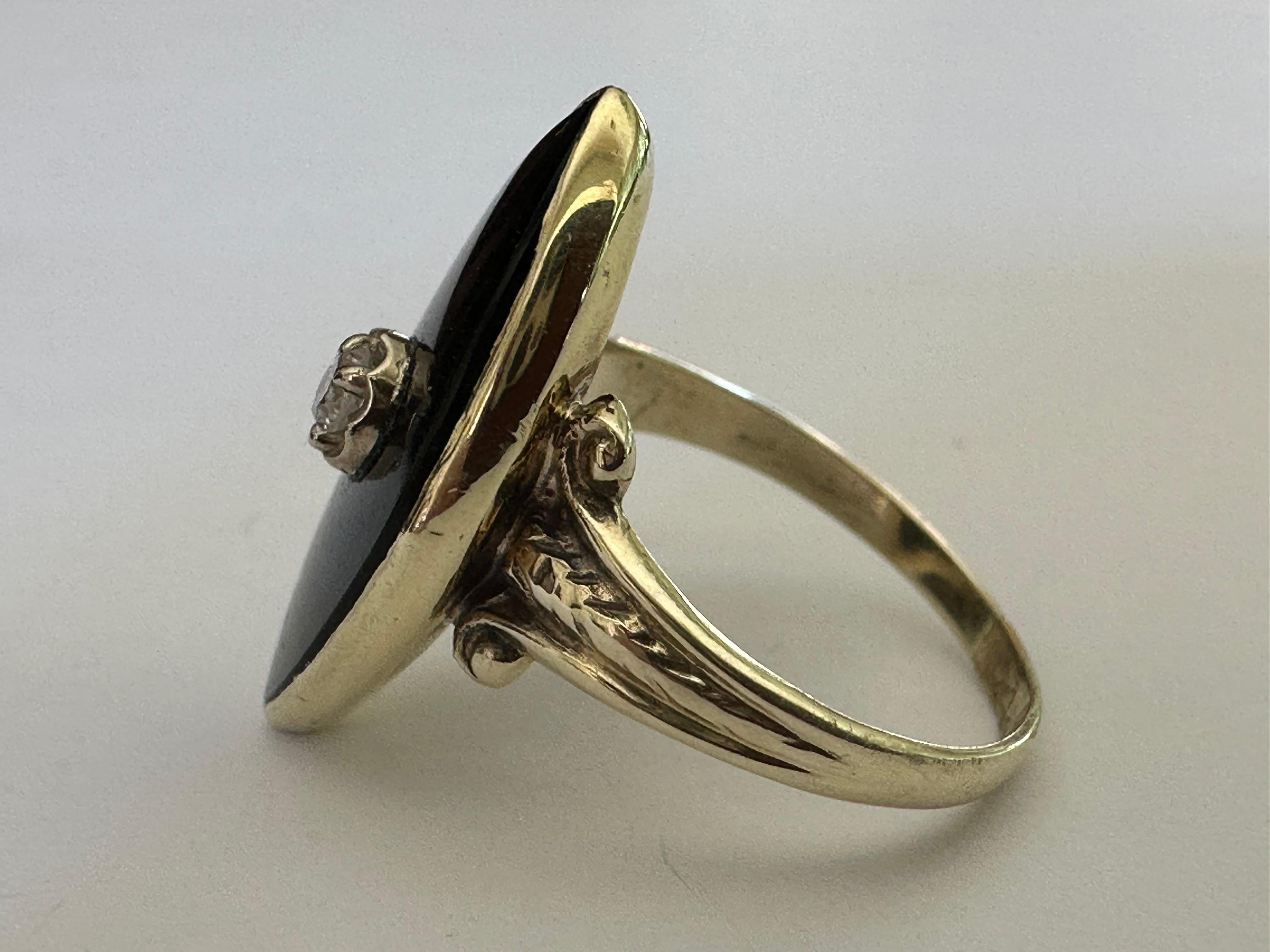 Realizzato negli anni '50, questo anello da pranzo di metà secolo è disegnato attorno a un'onice nera a forma di navetta trafitta da un piccolo diamante rotondo di circa 0,05 carati, colore HI, purezza SI2, e accentuato da spalle a forma di fleur de