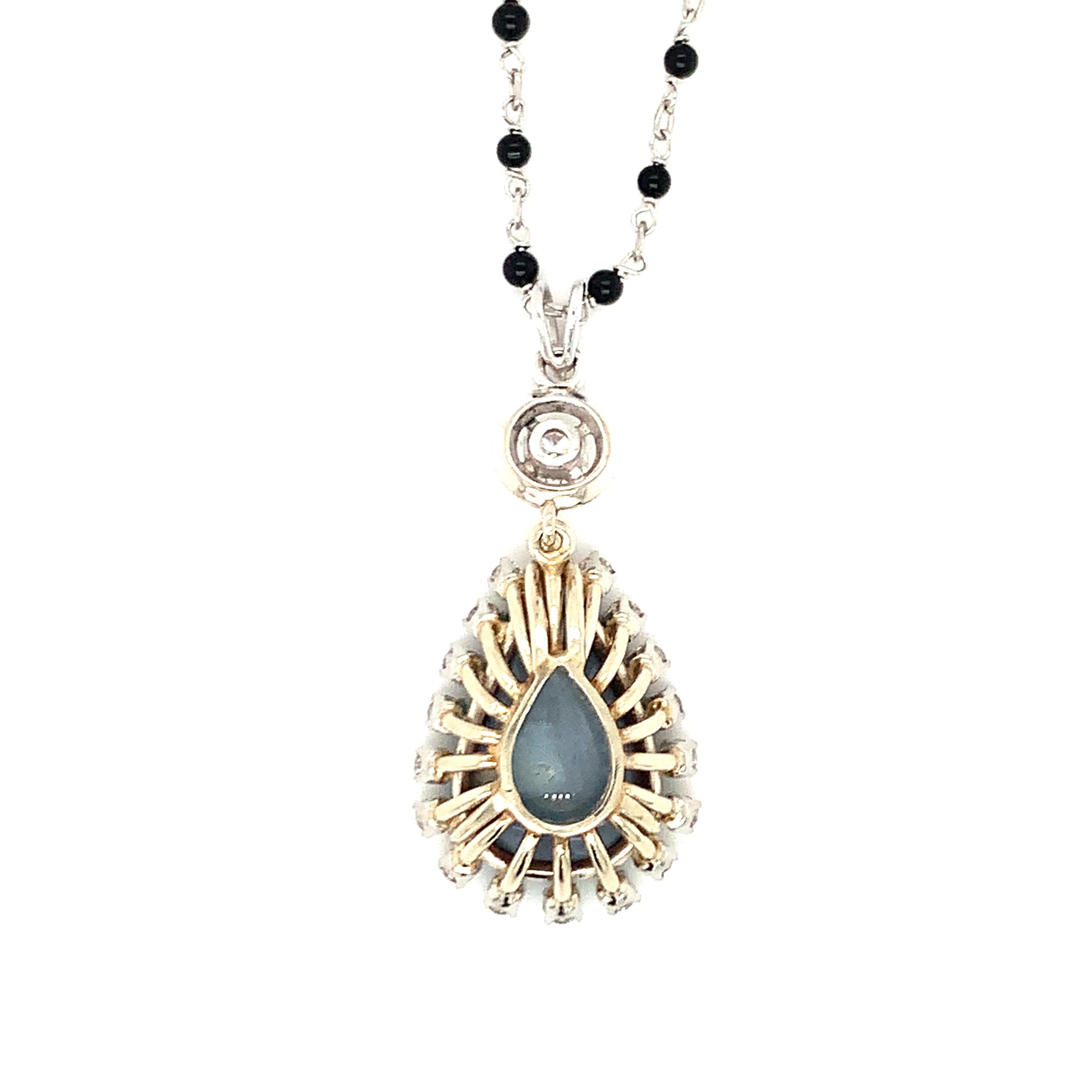 One black opal and diamond 18K white gold pendant centering one pear-shaped cabochon black opal weighing 4.50 ct. with 19 round brilliant cut diamonds weighing 0.80 ct. with I-J color and VS-1 clarity. Attached to an 18K white gold black onyx bead