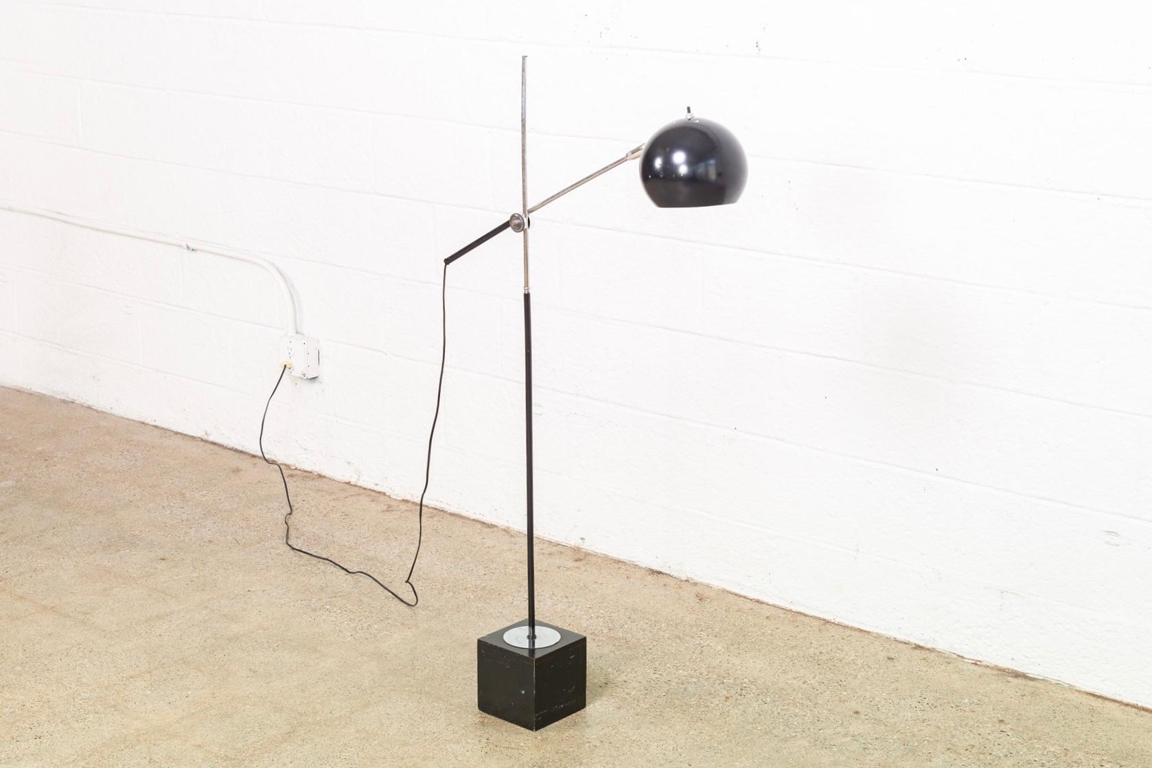 This vintage Mid-Century Modern single orb black articulating floor lamp in the style of Sonneman and circa 1970 has a clean modernist design. The swing arm rotates 360 degrees and can be raised and lowered vertically. The orb lamp shade pivots up
