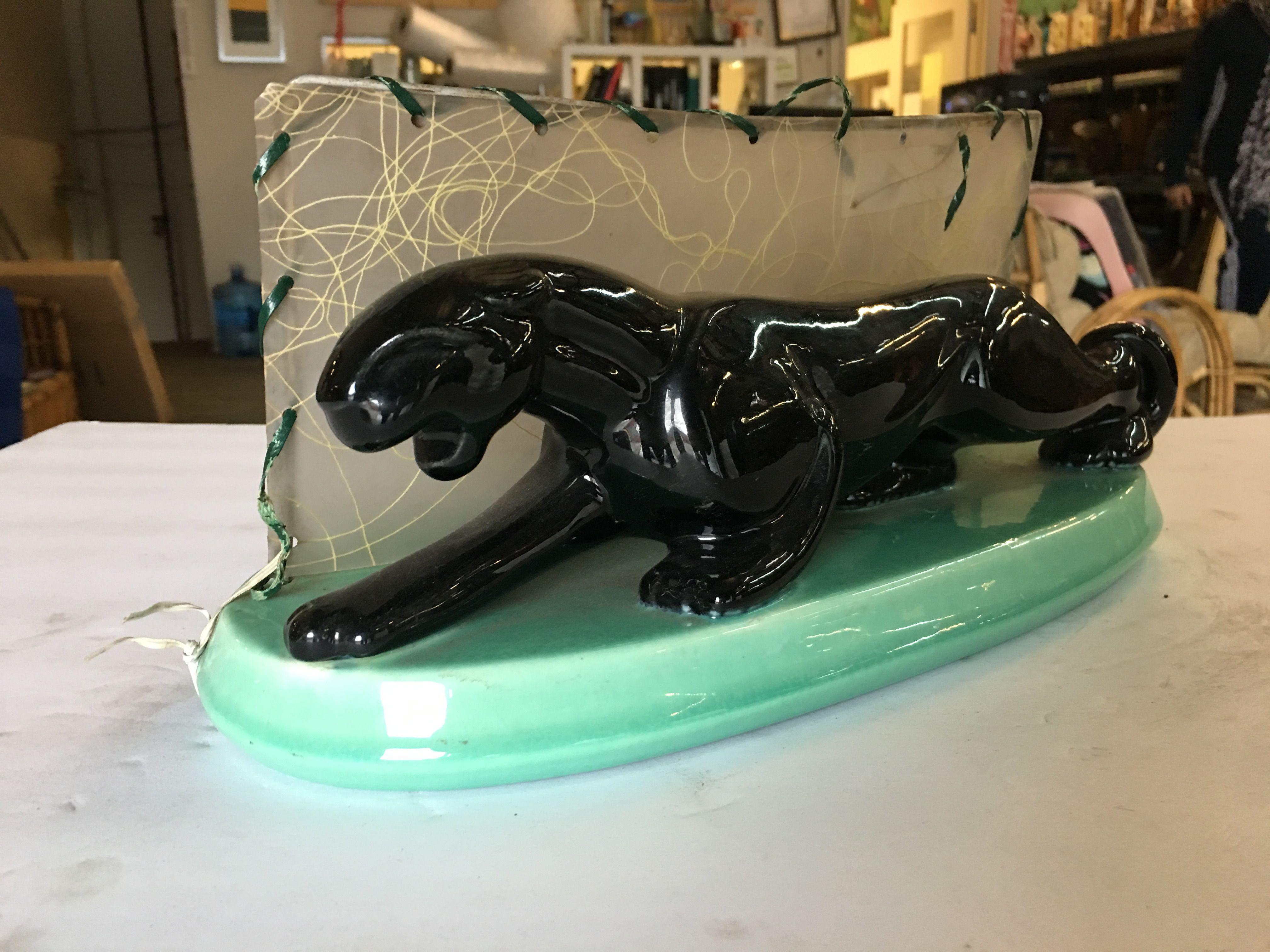 Midcentury panther art pottery ceramic statue lamp featuring a high glazed black finish and detailed form of a panther ready to strike with a backlit Whipple stitch fiberglass shade. This piece is 13 inches long.