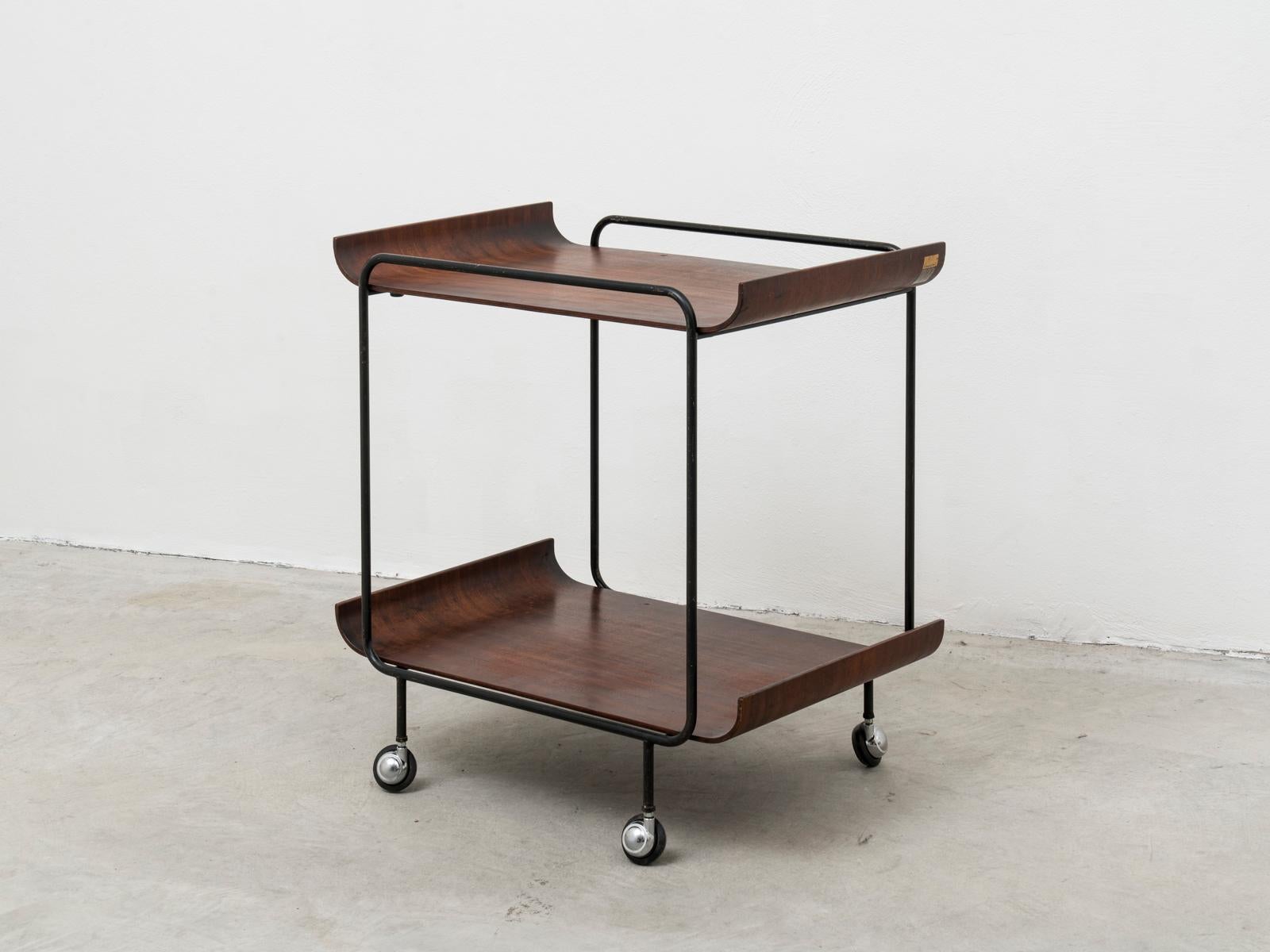This serving trolley was manufactured in Italy by Creazioni Stilcasa in the late 1960s.
It has a black-varnished iron structure in which two removable bentwood trays with rosewood veneer are set in place.
Both trays are labeled 
