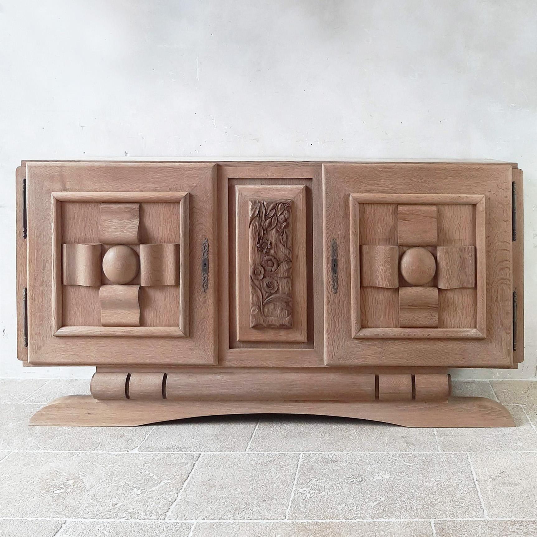 Mid century Bleached oak credenza by Charles Dudouyt , 1950s. Amazing Brutalist sideboard with doors cut in graphic and geometric shapes and the center panel has a beautiful wood carving in floral print. THe base gives this stunning piece a sturdy