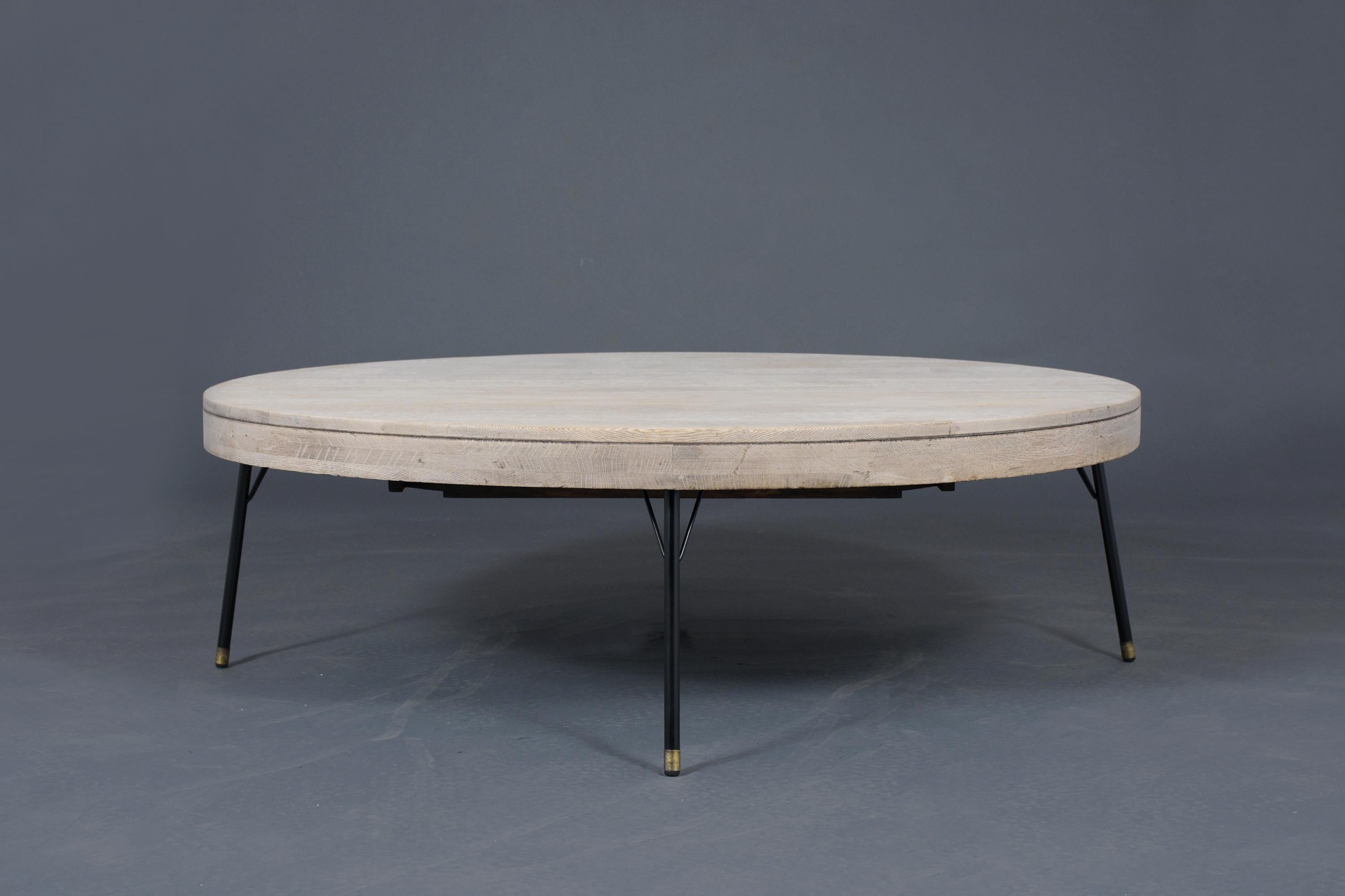 A Mid-Century Modern low coffee table crafted out of oak wood and has been professionally restored. It features a new bleached wood finish and sitting on four metal legs painted in black color with brass accents. The Modern Bleached Low Table is