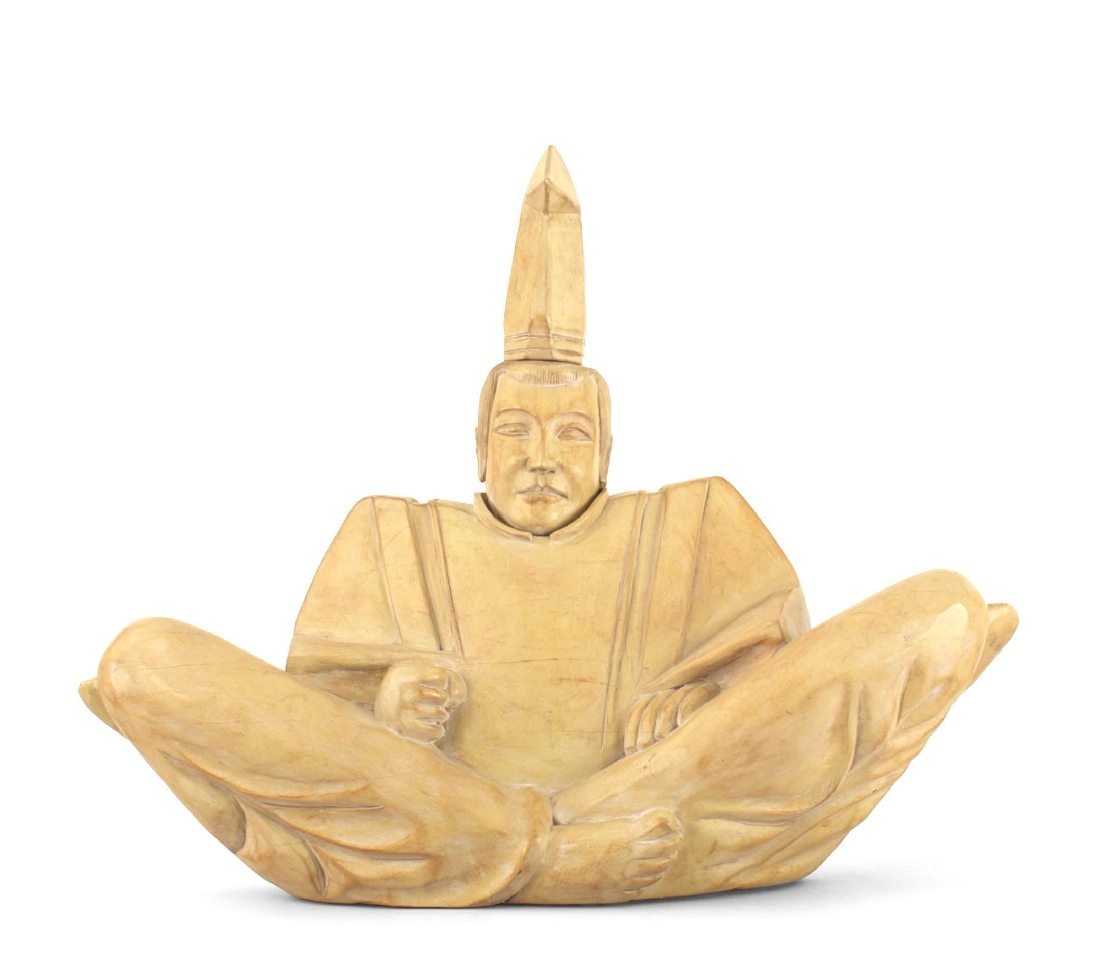 Figure religieuse sculptée en bois blanchi, de style asiatique japonais moderne du milieu du siècle, représentant un prêtre shinto assis en position du lotus, les jambes croisées.
