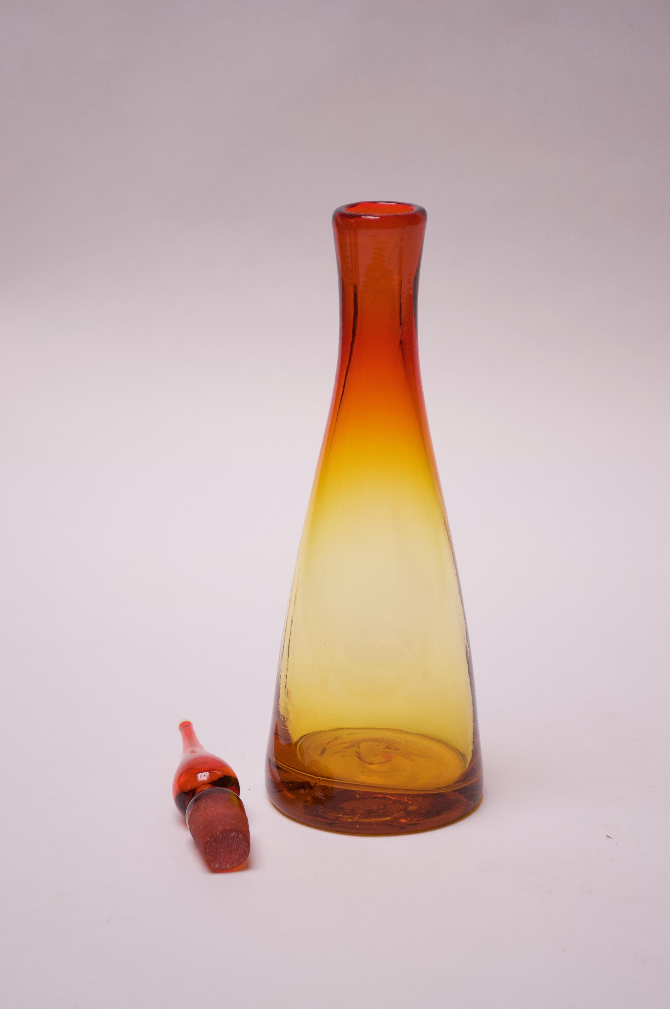 Blown glass decanter designed in the 1950s by Winslow Anderson for Blenko (model number 920-S). Unusual, diminutive size and striking amberina / tangerine palette with red and yellow meeting to produce an orange banding effect. 
Features Blenko's