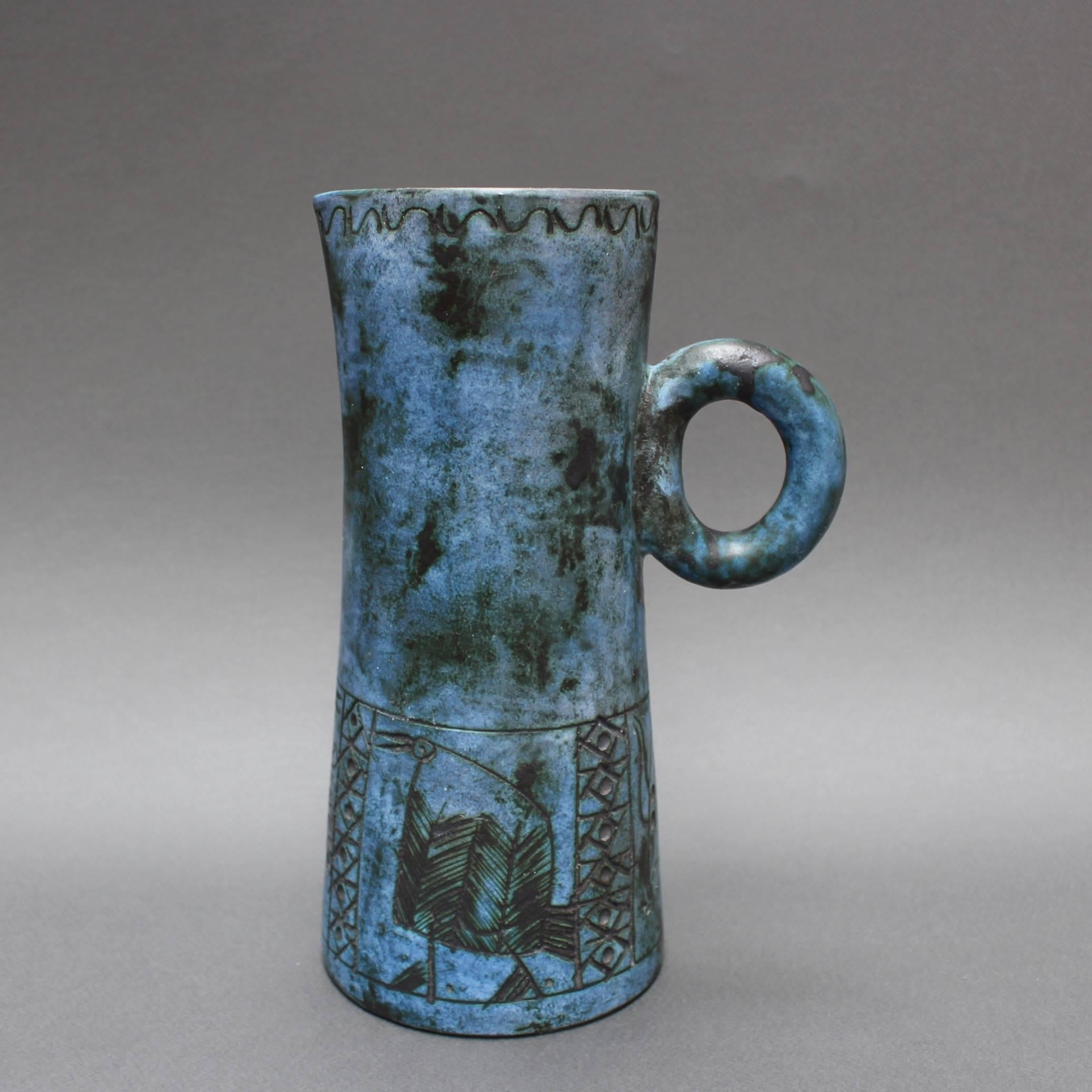 This elegant ceramic pitcher has Blin's trademark cloudy blue glaze featuring primitive images of birds and a bull, seemingly from an undiscovered cave, etched around the lower half of the vessel. The mouth also has a decorative surround motif. This