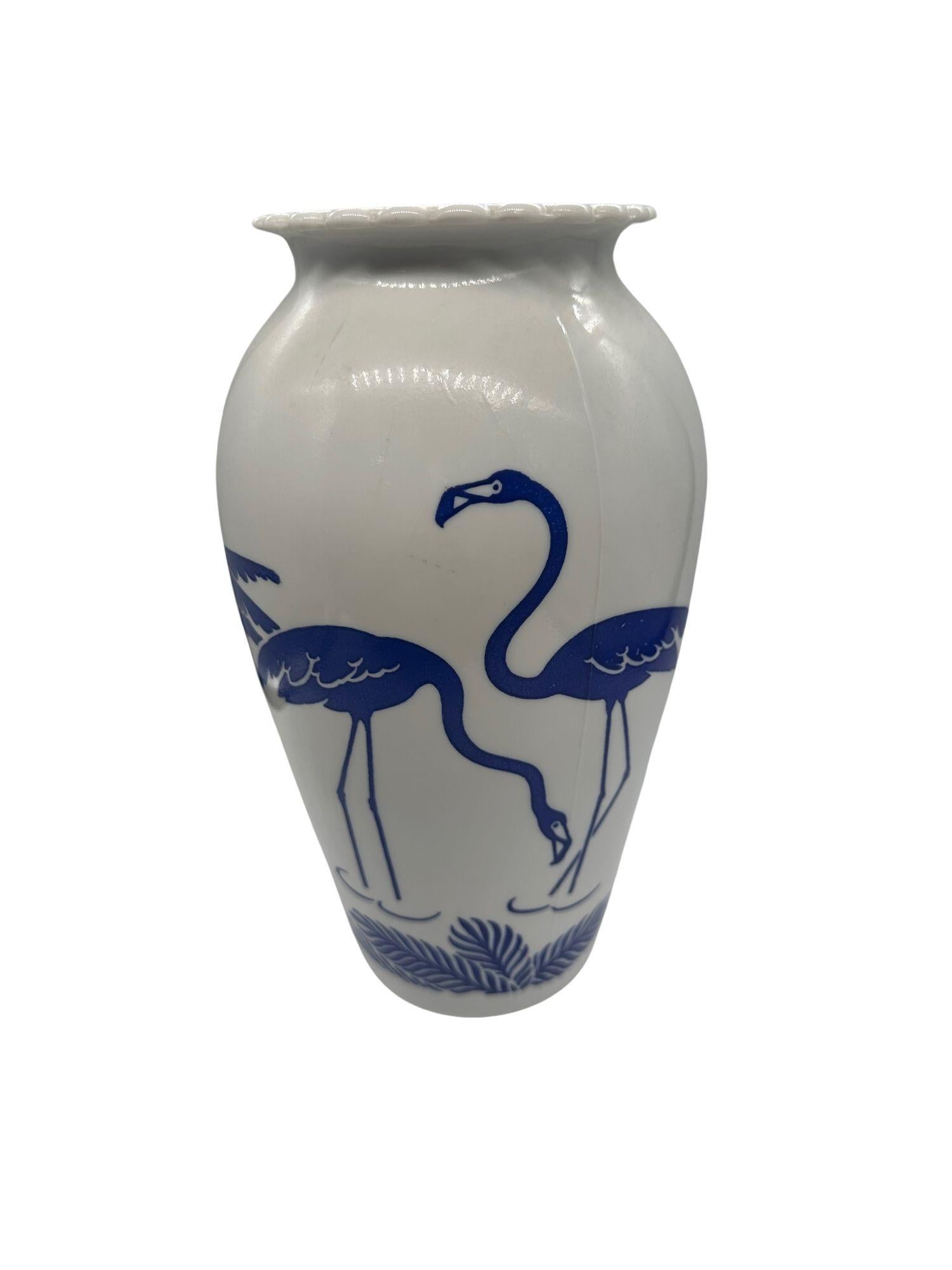 The Mid-Century Blue Flamingo Milk Glass Vase by Anchor Hocking Vitrock is a charming vintage piece that epitomizes the retro aesthetics of the mid-20th century. Crafted from milk glass, it features a delightful blue flamingo design, adding a touch