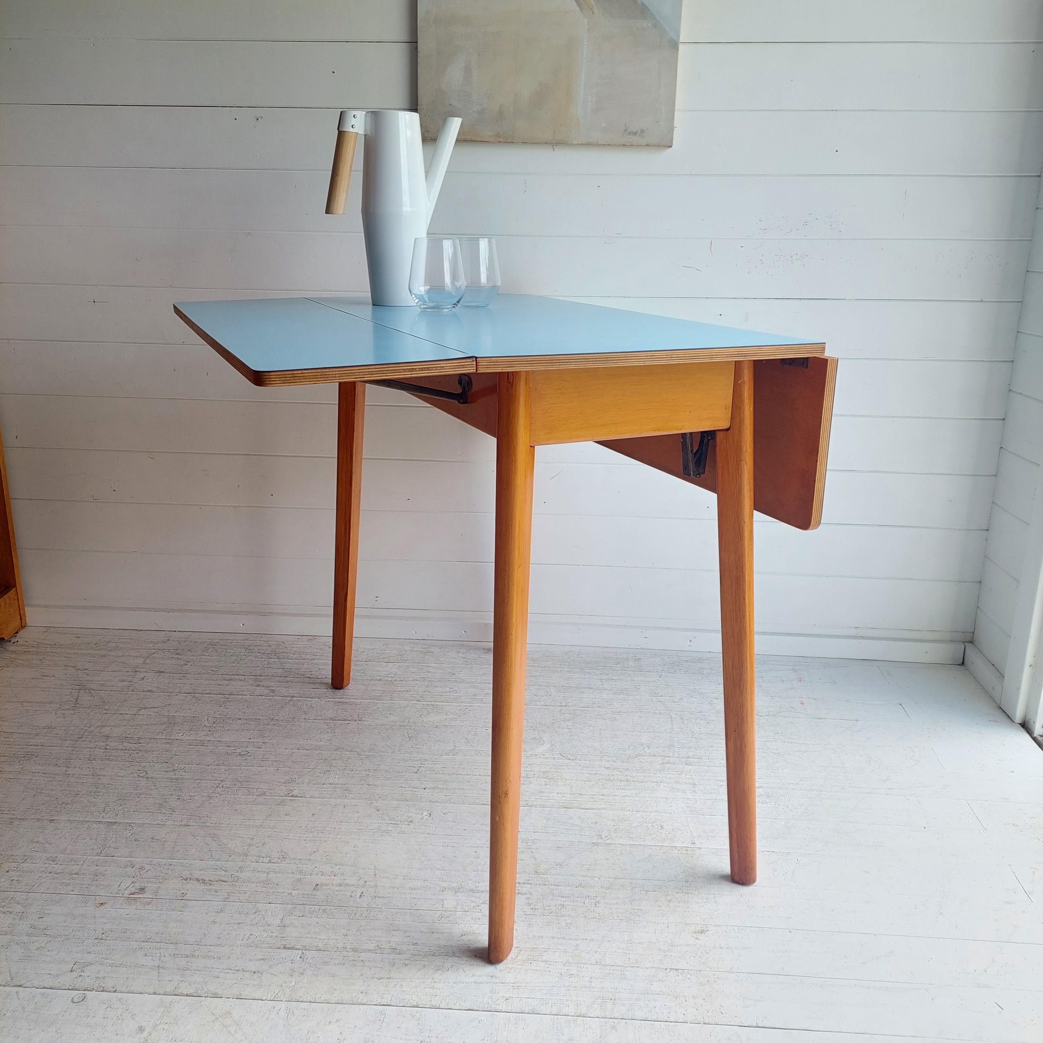 MID CENTURY DINING TABLE

CIRCA 1950s/60s

Original baby blue 1960's formica drop leaf table that seats 2-4 people
A great vintage addition to any small kitchen or living/dining room!
Beautiful baby blue formica topped kitchen dining table.
Sits