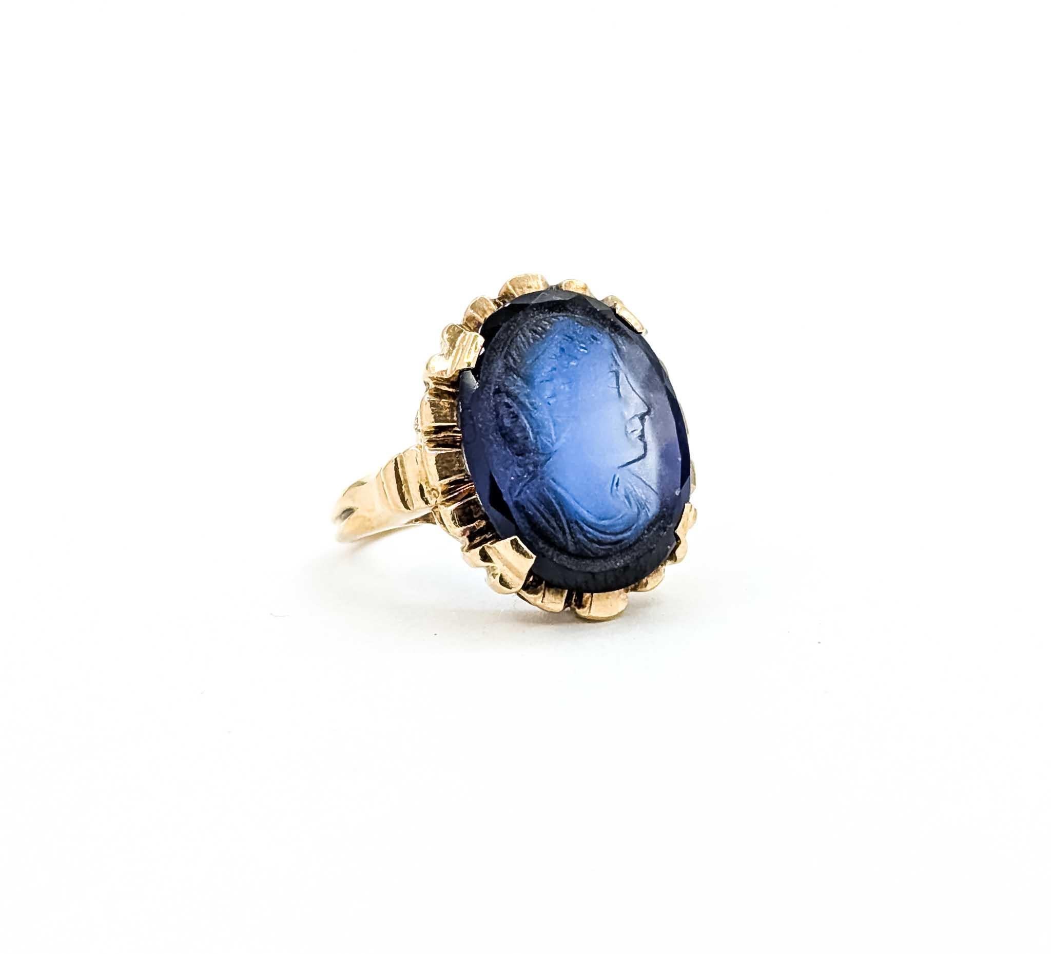 Introducing this beautiful Mid-Century ring crafted in 10k yellow gold. The ring features a striking blue glass cameo, delicately set to highlight its intricate design. The cameo presents a graceful profile, reminiscent of classical artistry, and is