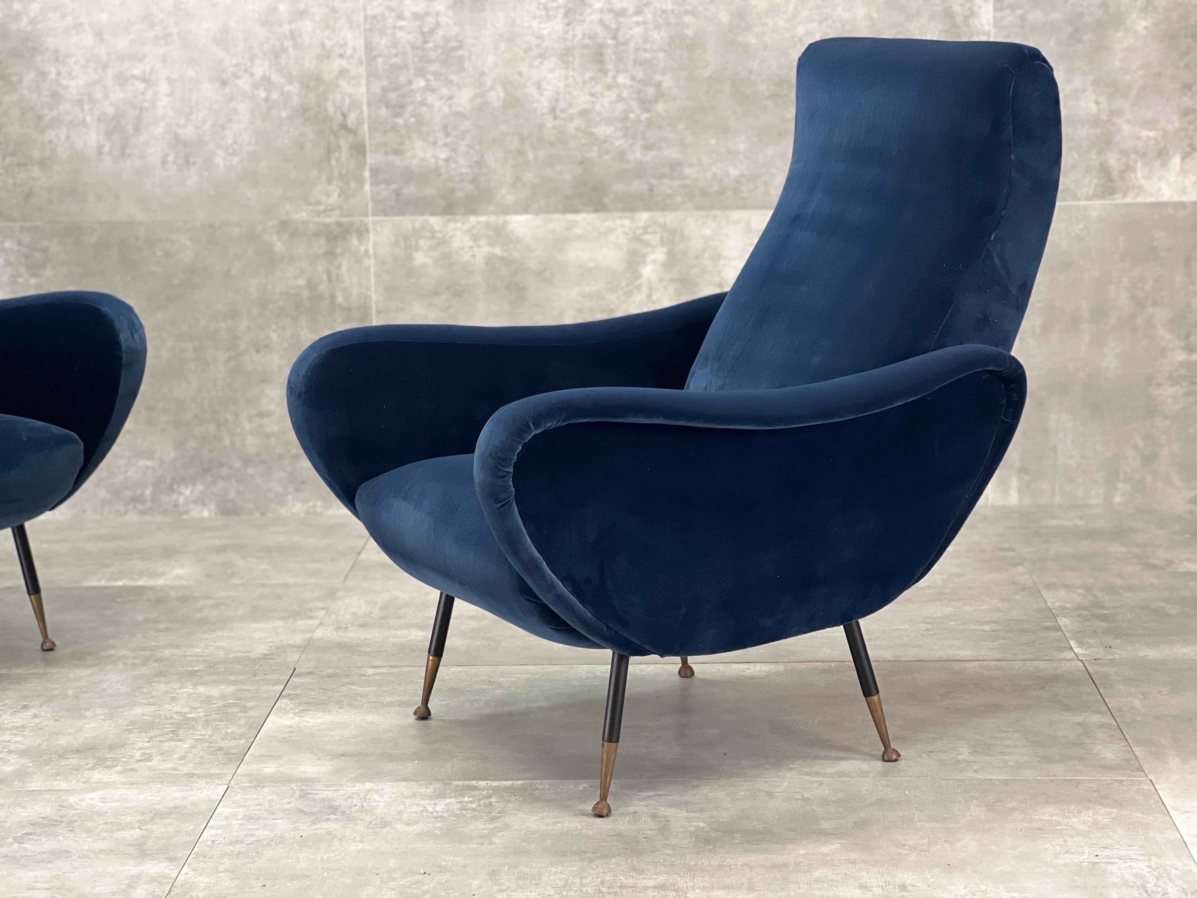 Mid-Century armchairs newly upholstered with blue velvet fabric, metal black legs and brass details.