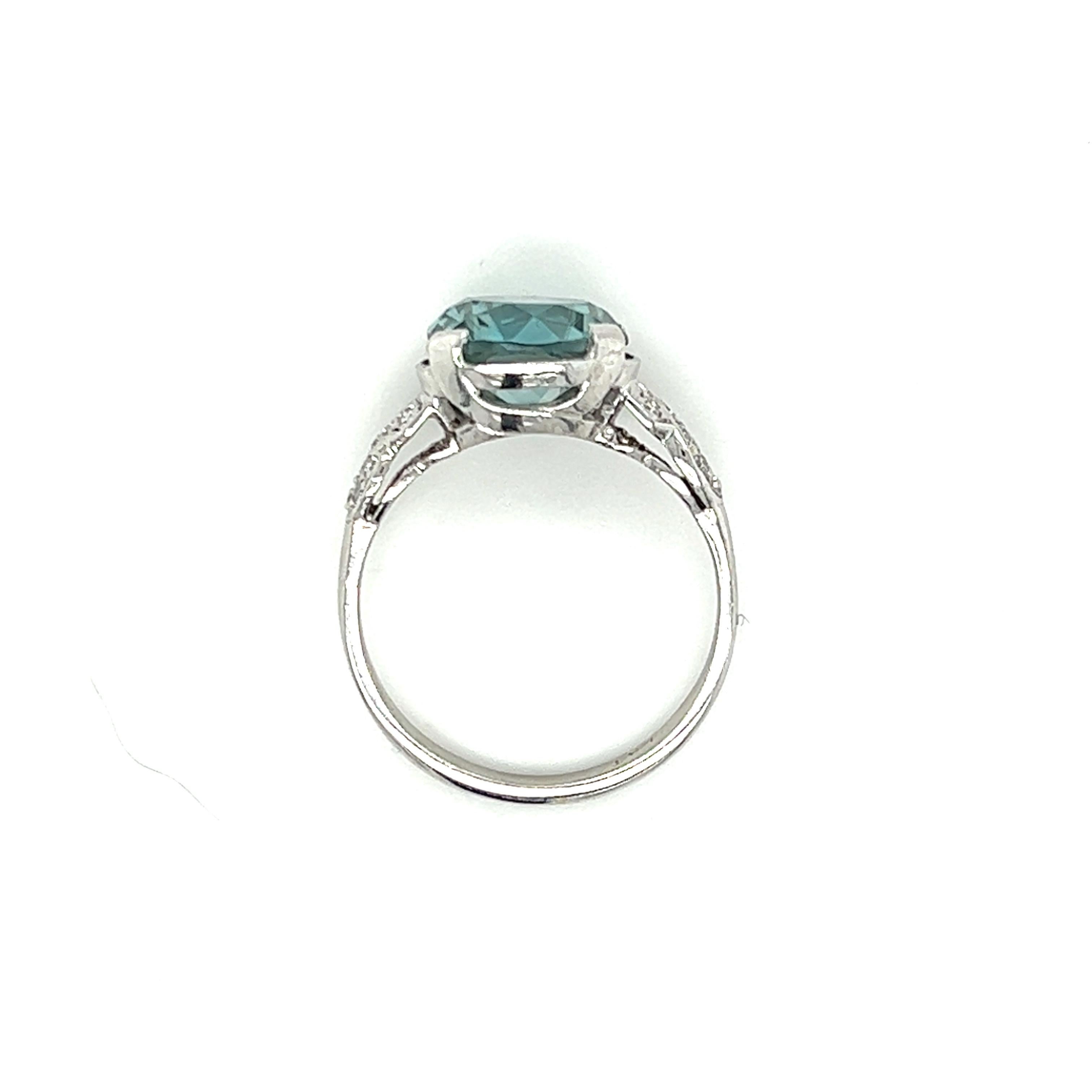 One platinum Retro design ring set with one 9.7mm round natural blue zircon stone, flanked by sixteen (16) round brilliant cut diamonds, approximately 0.15-carat total weight with matching H/I color and SI1 clarity. The ring is a finger size 6.5