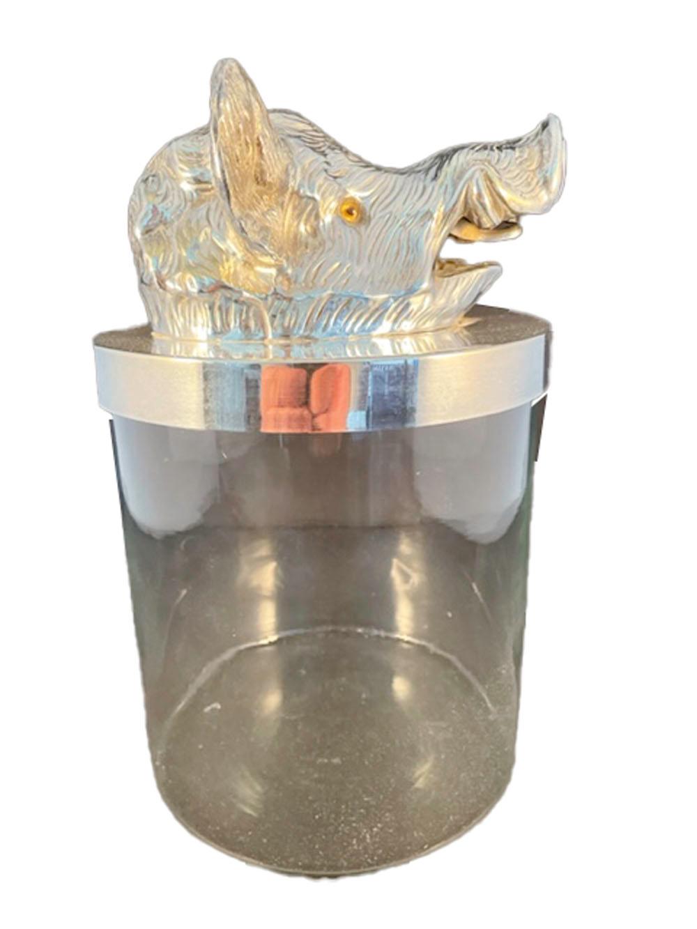 Bocal vintage en verre transparent de forme cylindrique avec un bord et un couvercle en métal argenté. Le couvercle comporte un modèle de tête de sanglier avec des yeux en verre. Attribué à Valenti, Espagne.