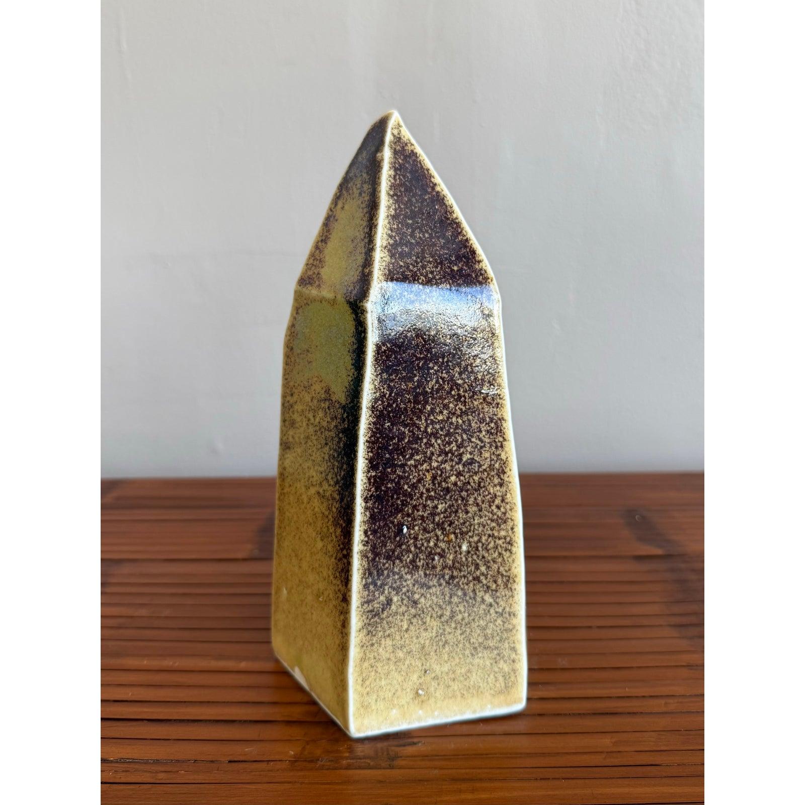Este escultural reloj de cerámica es una pieza destacada del diseño moderno de mediados de siglo, que combina la geometría brutalista con el trabajo orgánico del esmalte. Hecha a mano y cocida con esmero, su atrevida forma angulosa se eleva hasta un