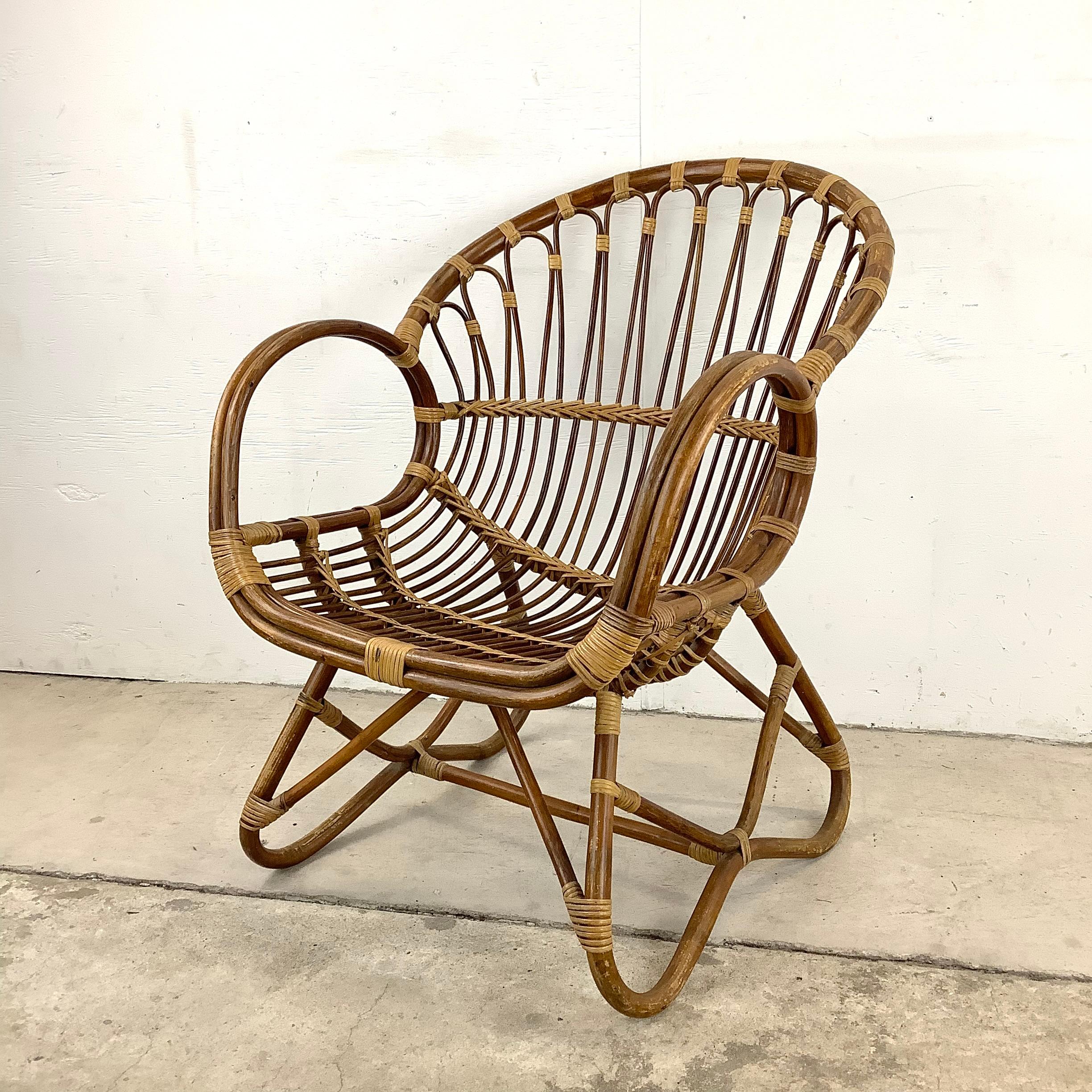 This impressive vintage boho modern arm chair features chic bamboo rattan construction in a uniquely shaped design. A throne armchair for any setting, this mid-century bamboo side chair brings a uniquely eclectic vibe to every