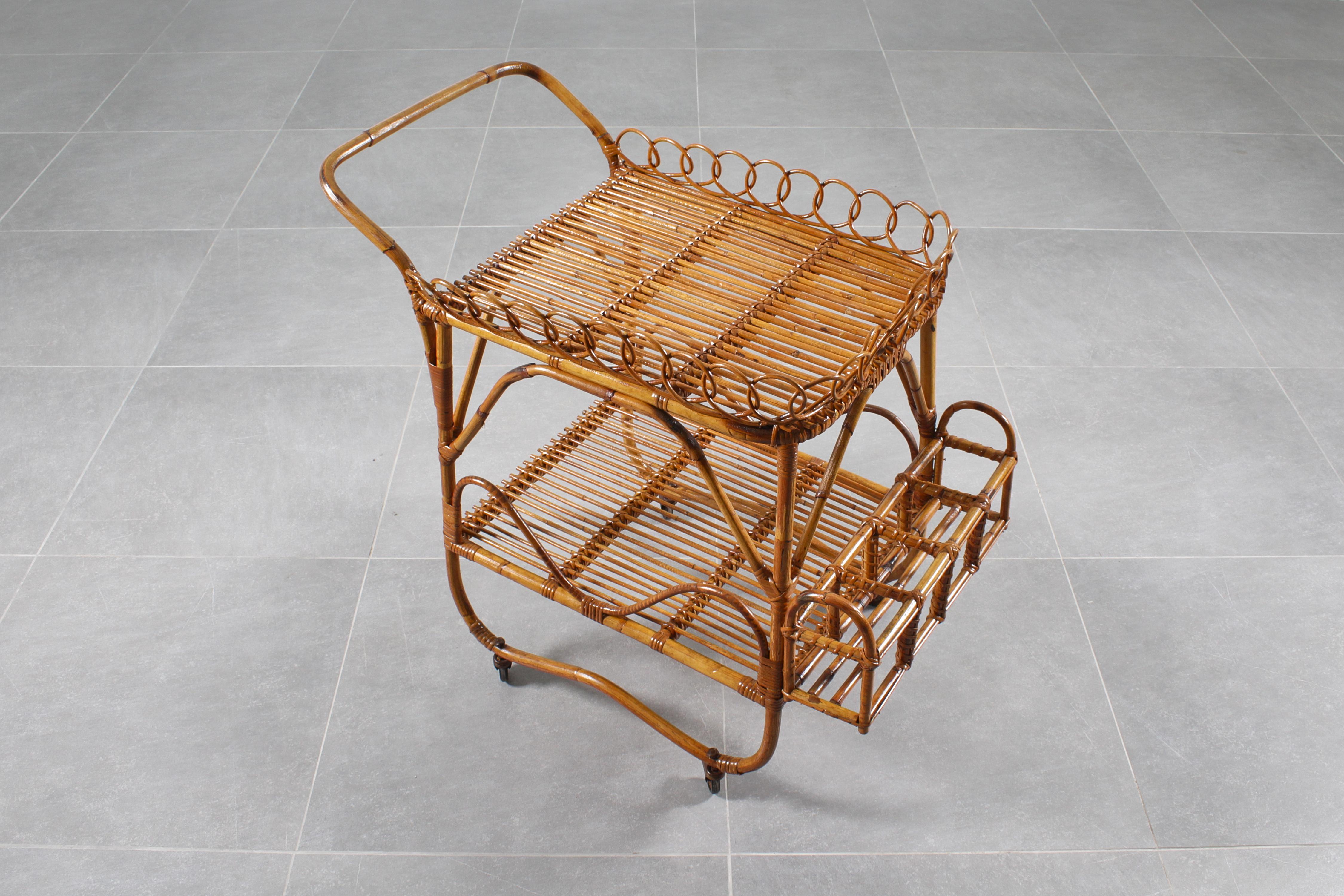 Elegant and rustic bar trolley in bamboo cane and rattan, with two large tops, handle, protruding bottle holder, resting on four wheels. Attributable to Bonacina, Italian manufacture from the 1960s
Wear consistent with age and use.