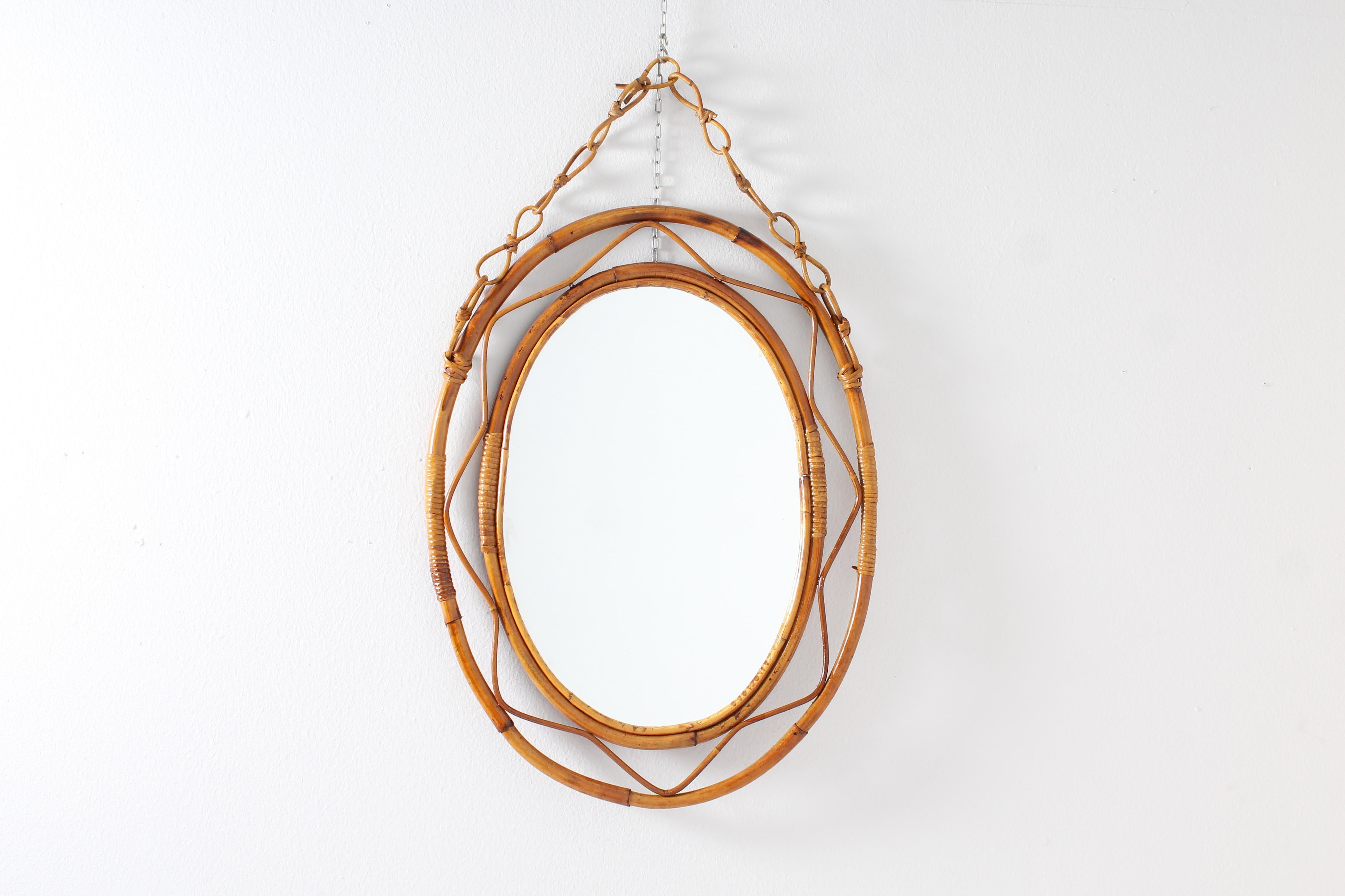 Stylish oval mirror with double frame and chain in curved bamboo cane and wicker band elements. Italian manufacture attributable to Bonacina, 1960s.
Wear consistent with age and use.