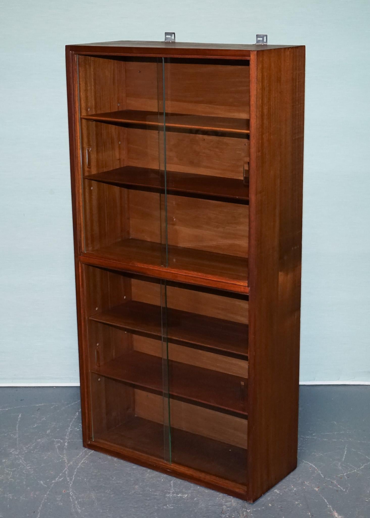 
Antiques of London



A minimalist mid-century modern wall-mounted display cabinet, perfect for showcasing collectables, books, or decorative pieces. Crafted with a warm wood veneer and featuring five adjustable wooden shelves behind smooth sliding