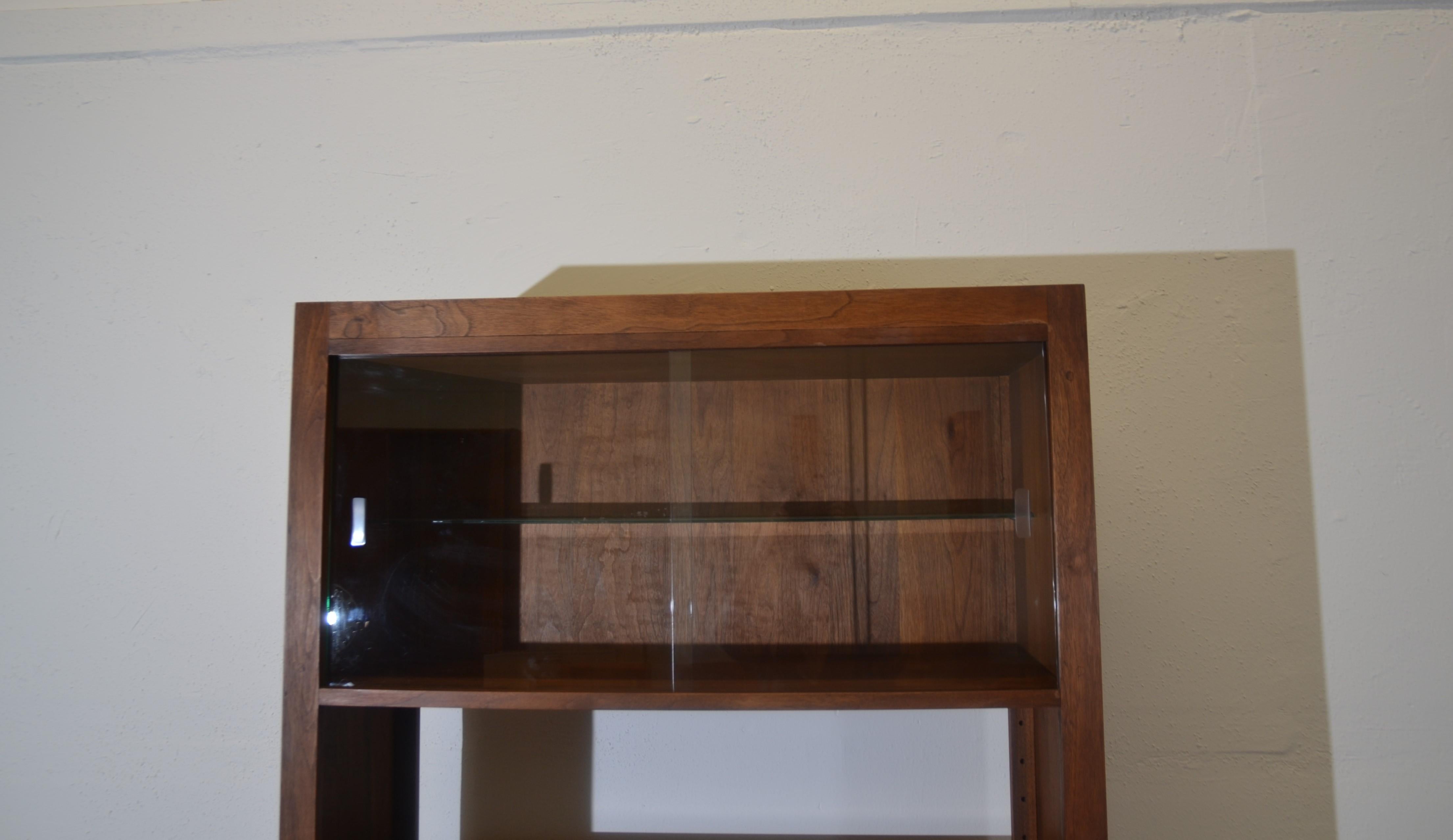 Mid-century bookcase. The top has sliding glass doors, the middle has open shelves the bottom has storage.