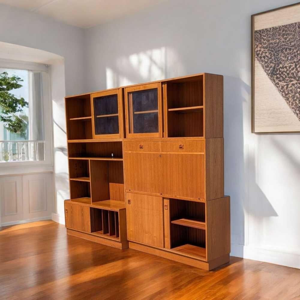 A distinctive freestanding bookcase in the mid-century modern tradition, crafted from teak veneer and showcasing clean lines, modular construction, and a blend of open and closed storage. This piece blends timeless Scandinavian design with