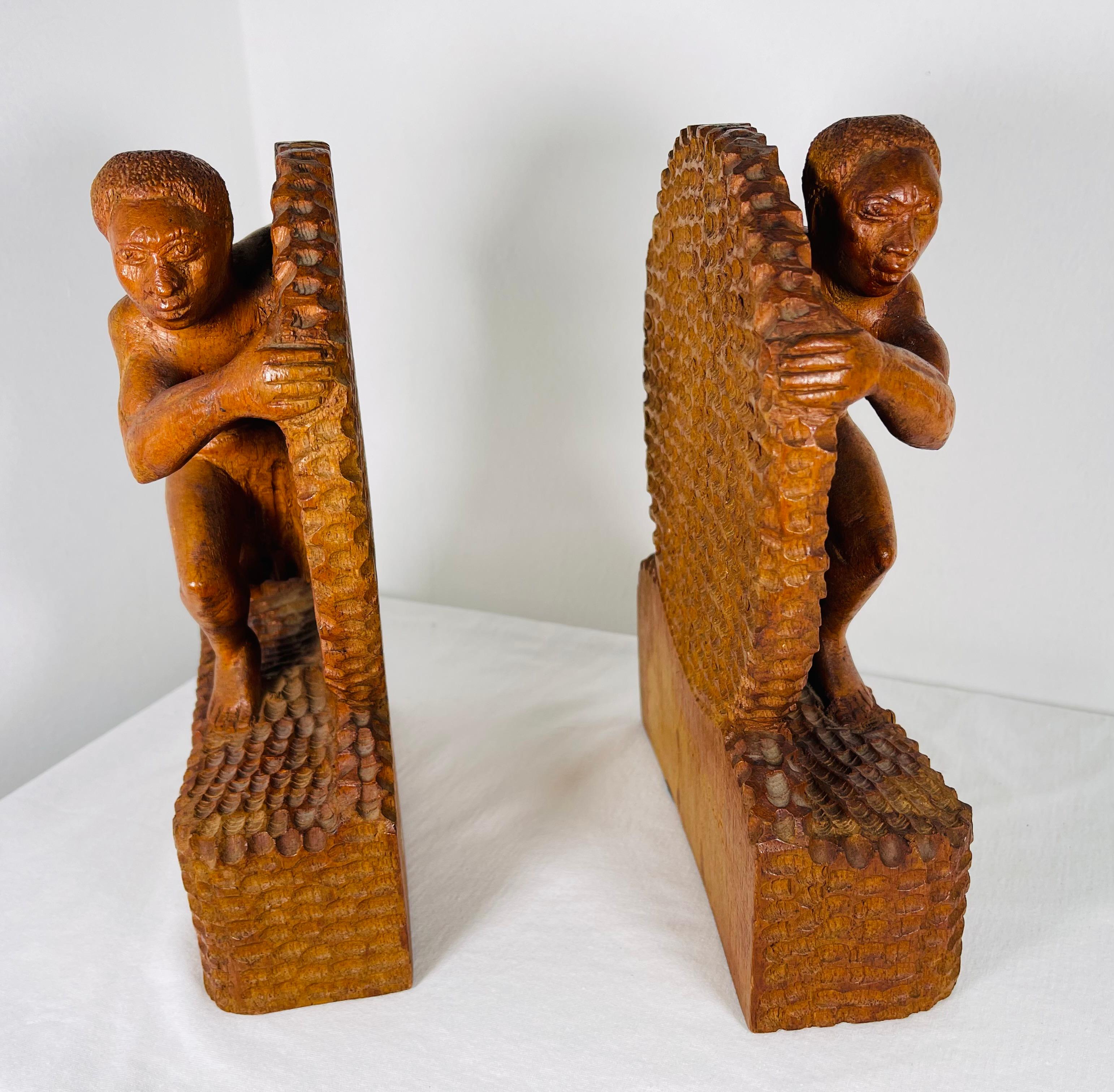 Deux serres d'époque Art Déco livrées sculptées en palissandre d'origine signées B Ralisam
La sculpture représente deux hommes presque nus dans l'effort de l'œuvre. Ils poussent une roue avec un support pour les pieds. Les muscles des personnages