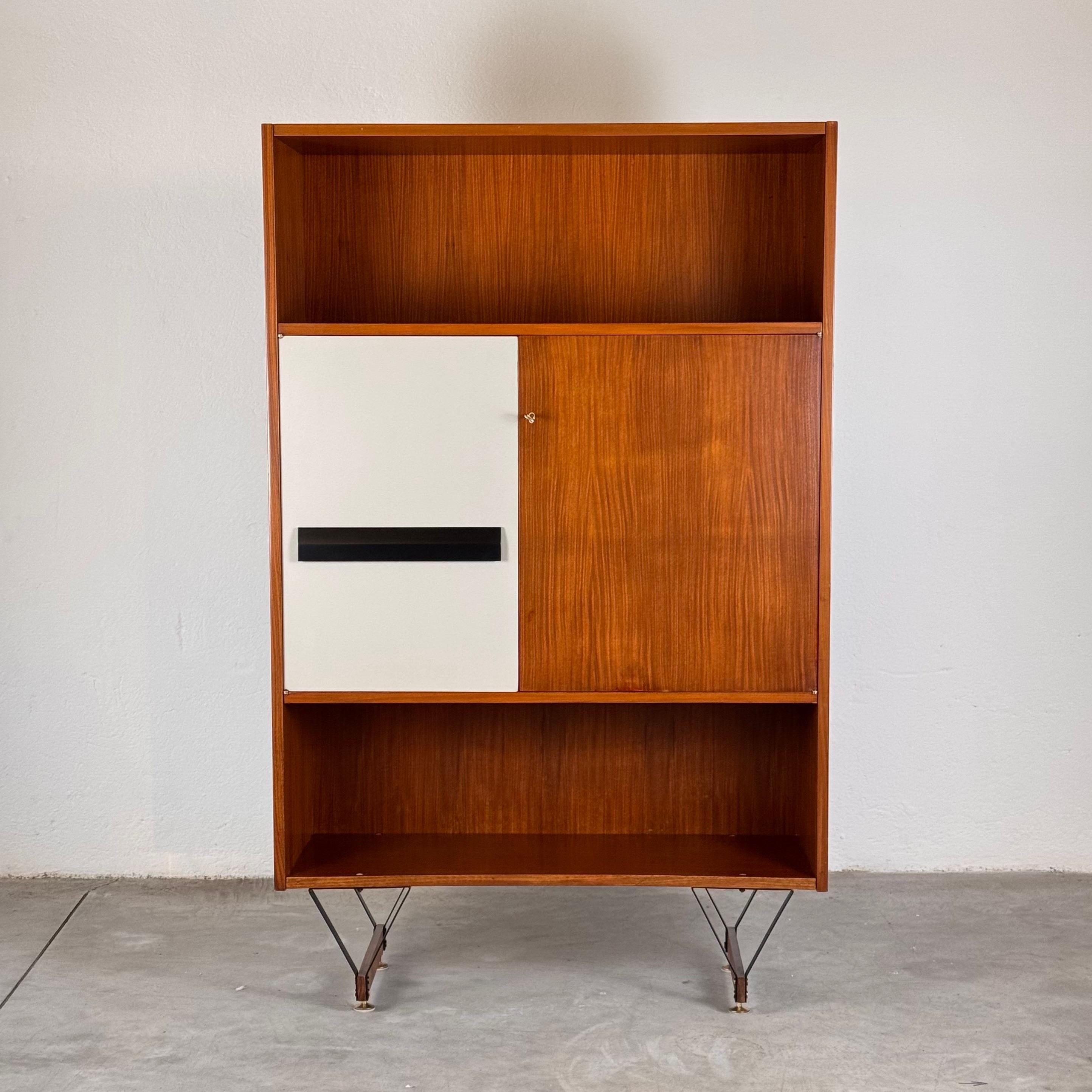 An exquisite mid-century modern bookshelf and cabinet, designed by the renowned Enzo Strada and crafted by Fratelli Tenani in the 1960s. This elegant piece showcases a masterful combination of teak wood, brass, and painted metal, resulting in a