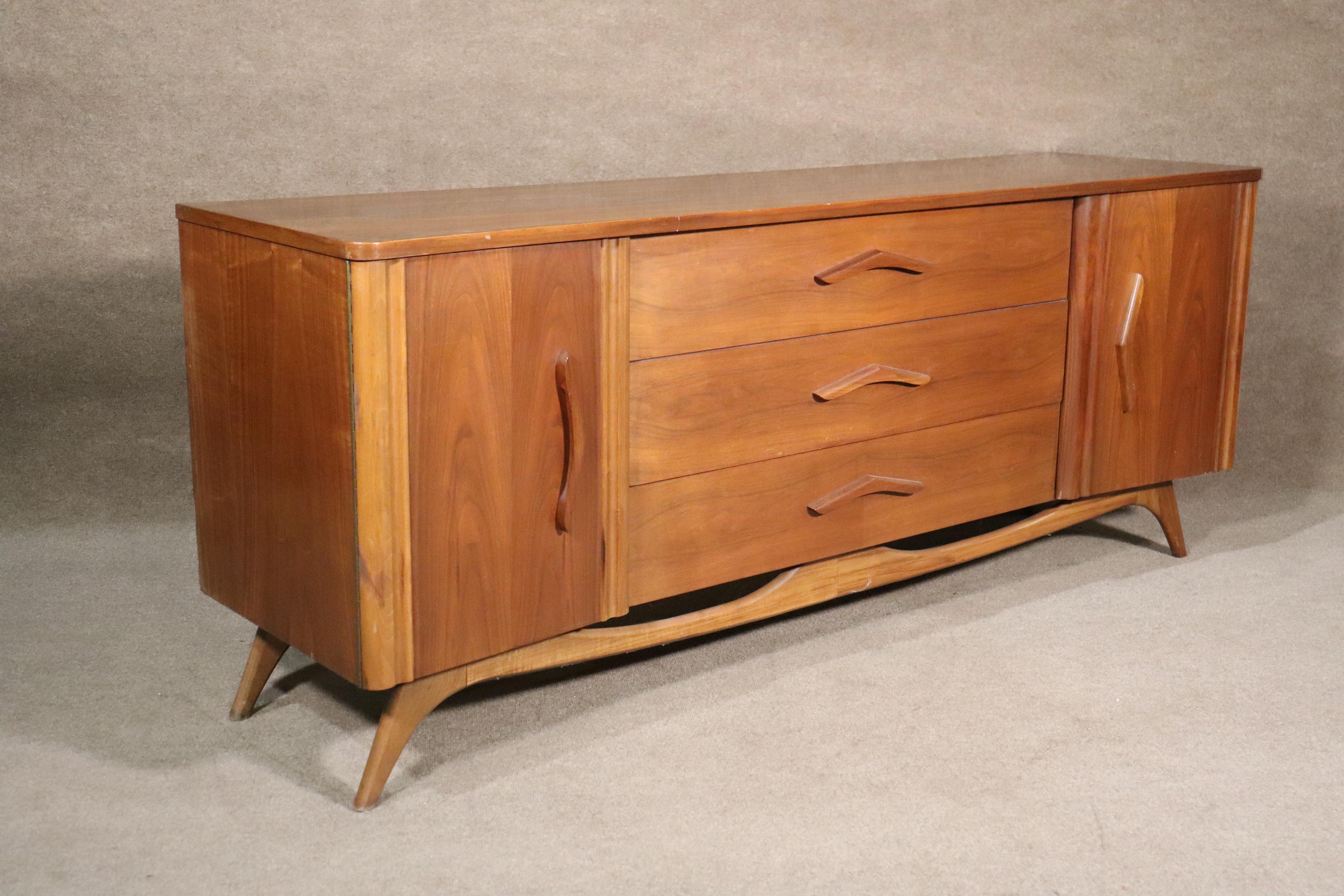 Long American walnut dresser with nine drawers. Features organic boomerang handles and matching sculpted base.
Please confirm location.
