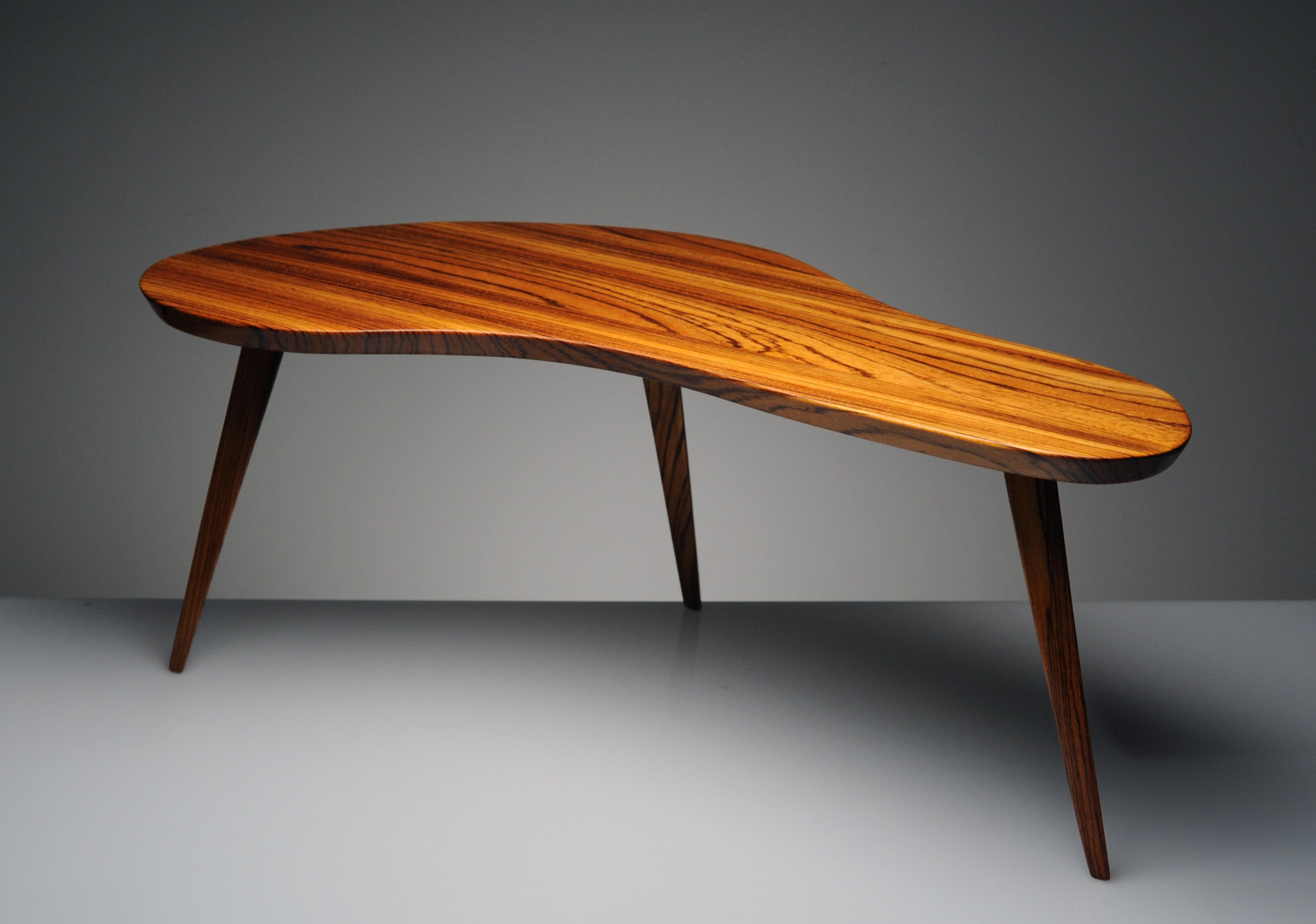 Beautiful handcrafted boomerang shaped coffee table made from solid Zebrawood. Striking grain throughout and beautifully shown with beveled edge and three solid triangular wood legs. Details of the table also reveal a beautiful bird's-eye pattern
