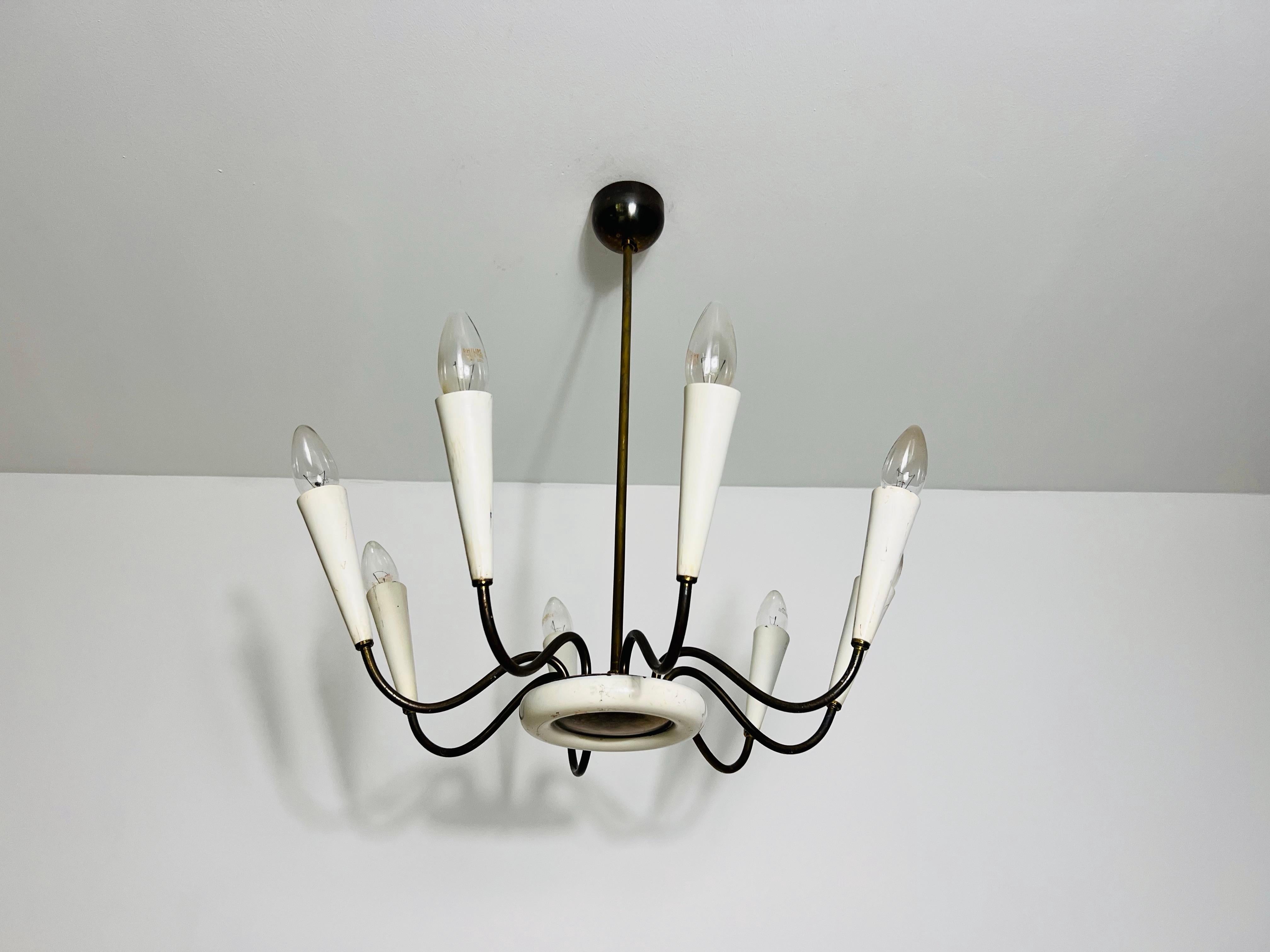 Questa dinamica lampada da soffitto, proveniente dall'Italia degli anni '50, combina un tocco sportivo con un elegante design di metà secolo. L'apparecchio è caratterizzato da bracci in ottone e da una base elegante verniciata di bianco, che insieme