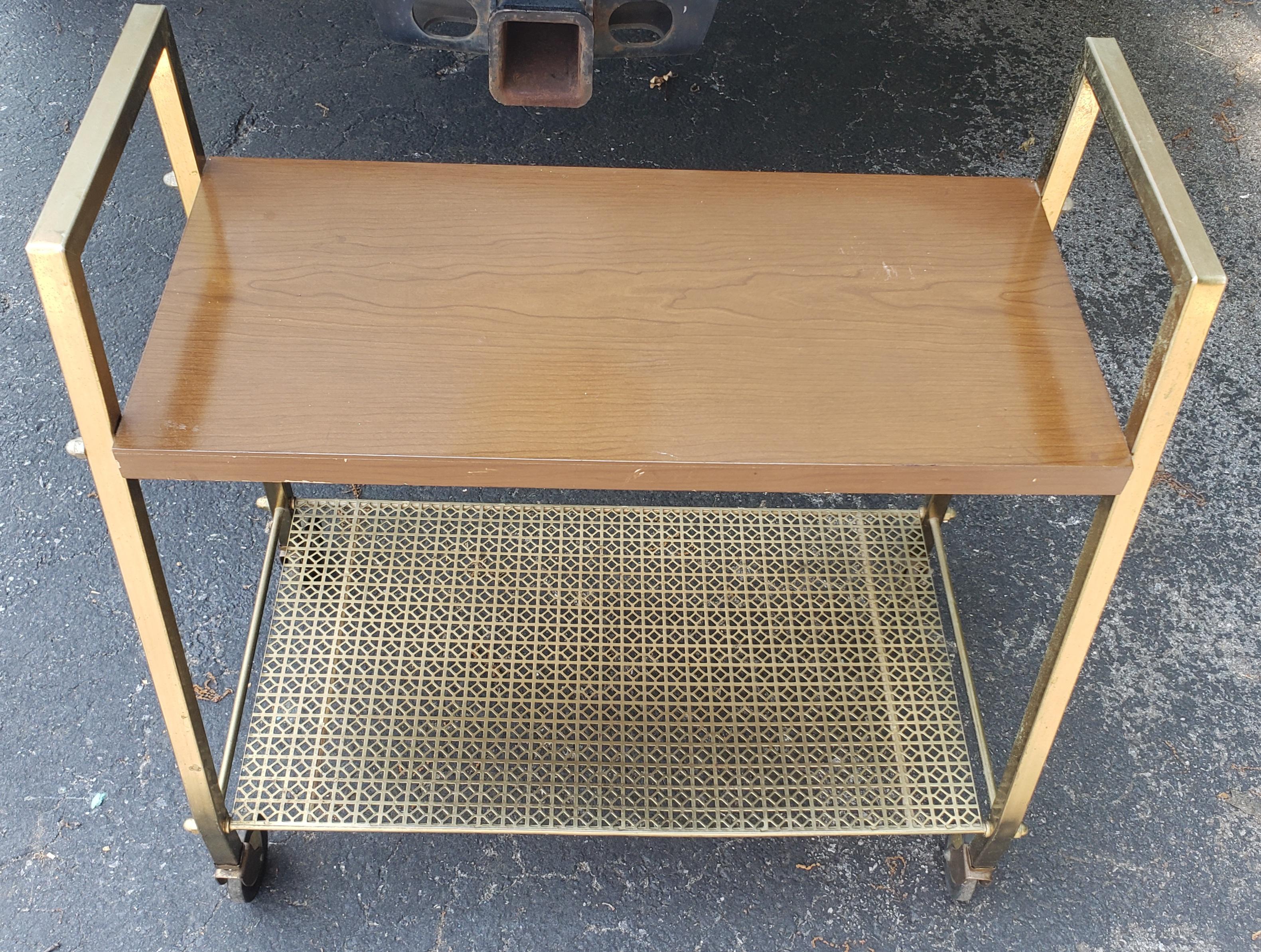 A midcentury Brass and Formica top Rolling Cart. Measures 25