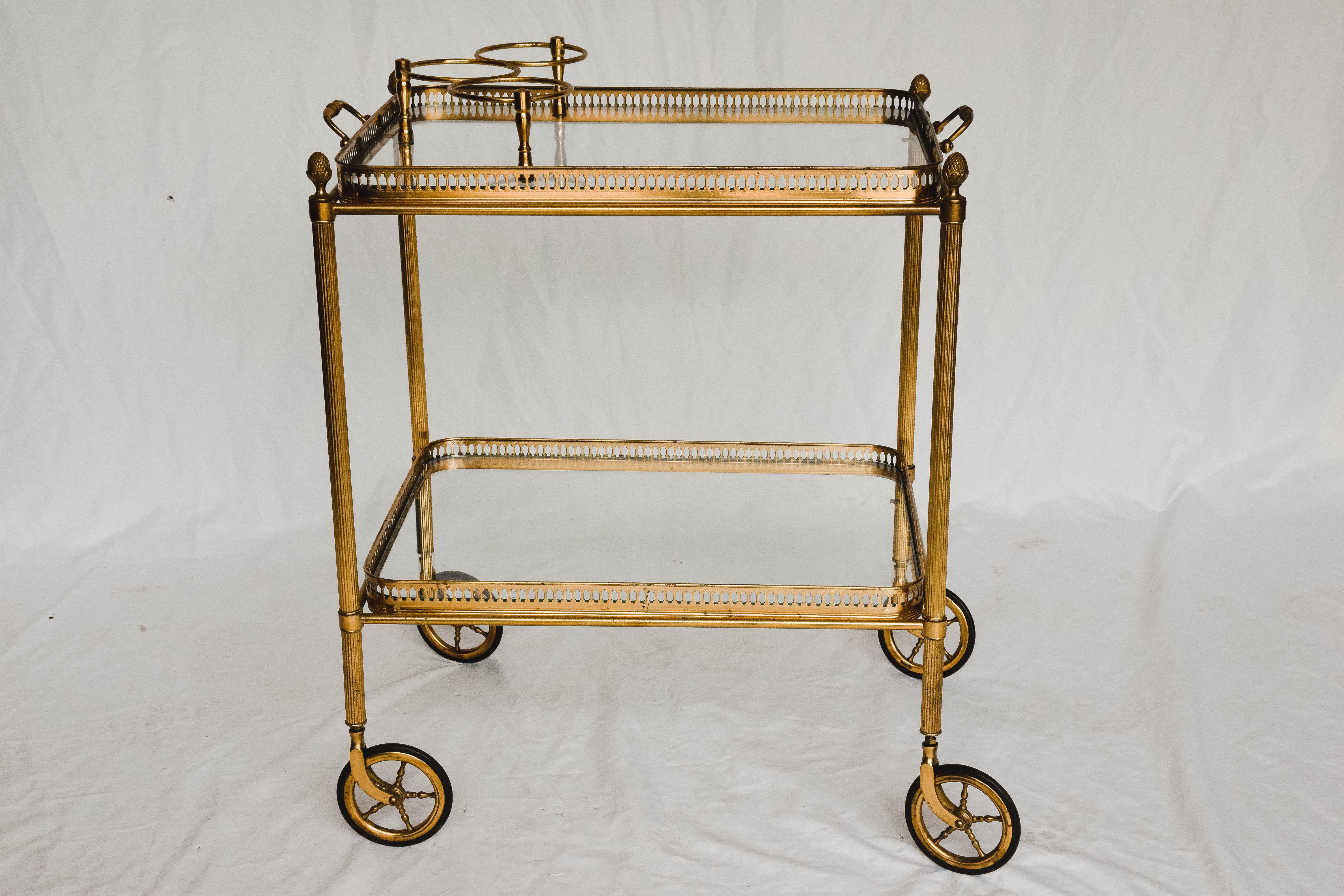 This Mid-Century Modern bar cart is sure to delight. Constructed of brass and glass bringing beauty to the midcentury design. The two glass tiers provides ample space for all your bar needs. It also provides a rack to hold three bottles.