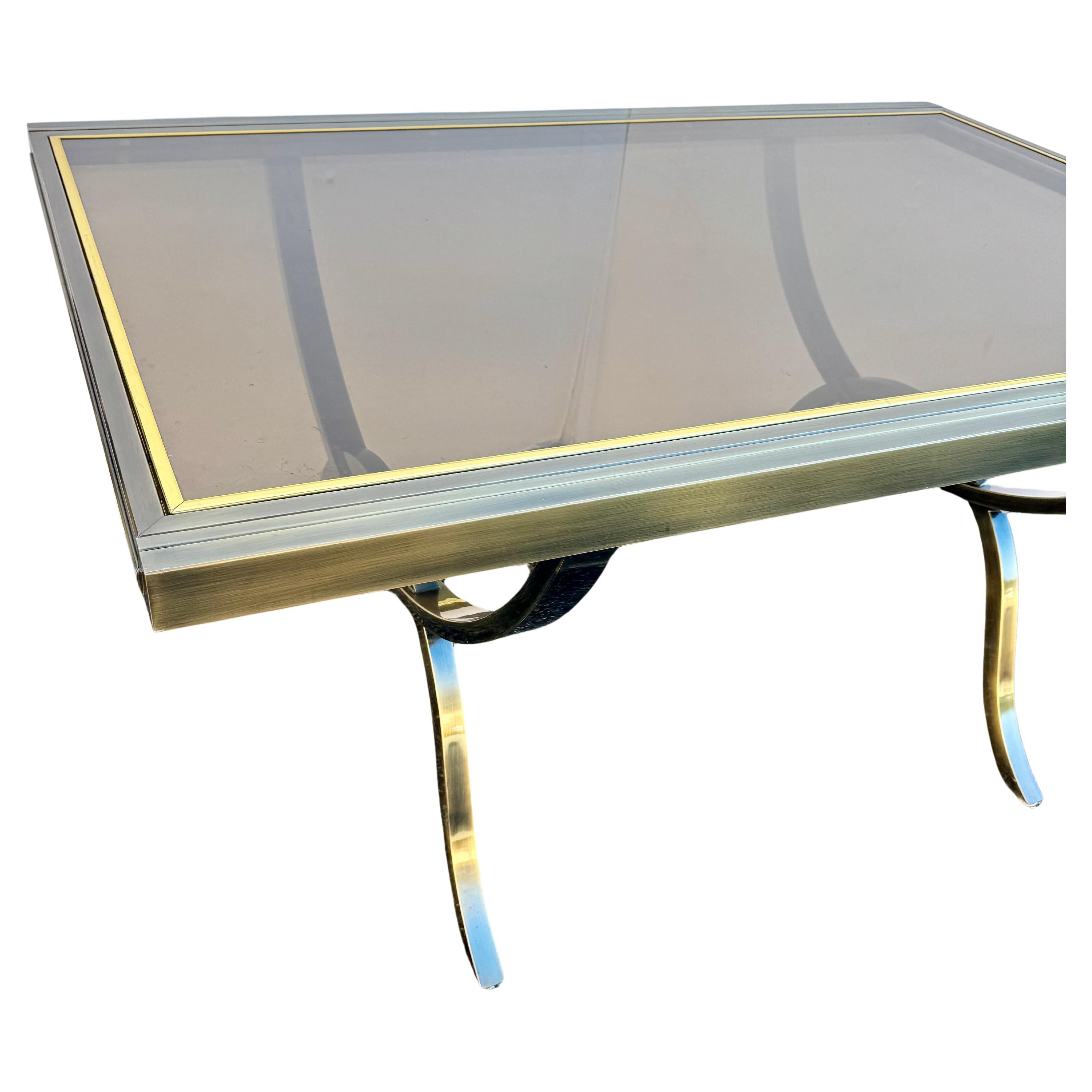 Fantastic Mid-Century Modern extendable chrome, brass and smoked glass curule legs dining table designed by Milo Baughman for the Design Institute of America. The table easily expands with built-in leaves that double the width of the table (extends