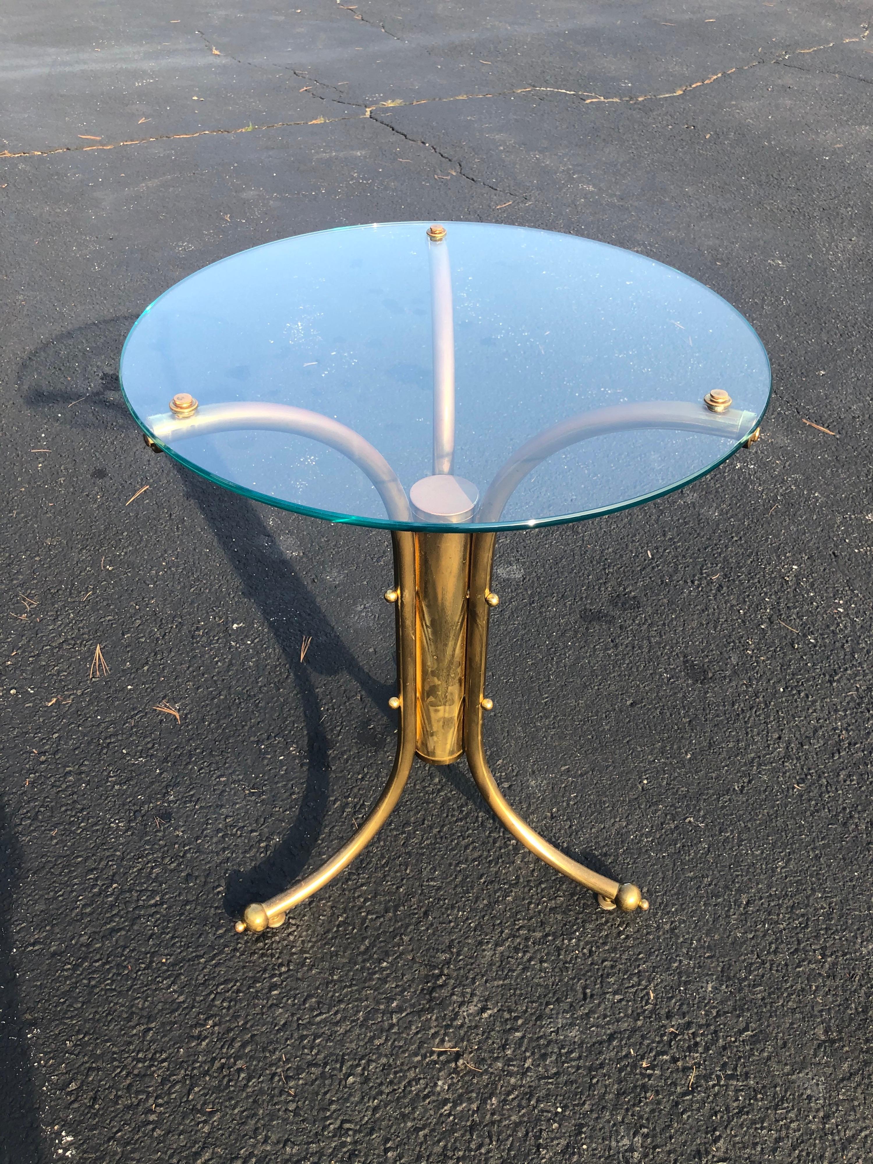 Midcentury brass and glass bistro table. Just add two chairs. Classic round glass top with elegant tripod base. Can be used to dine at or as a plant stand. 1970s in the style of Karl Springer. Please confirm the dimensions prior to purchase. This