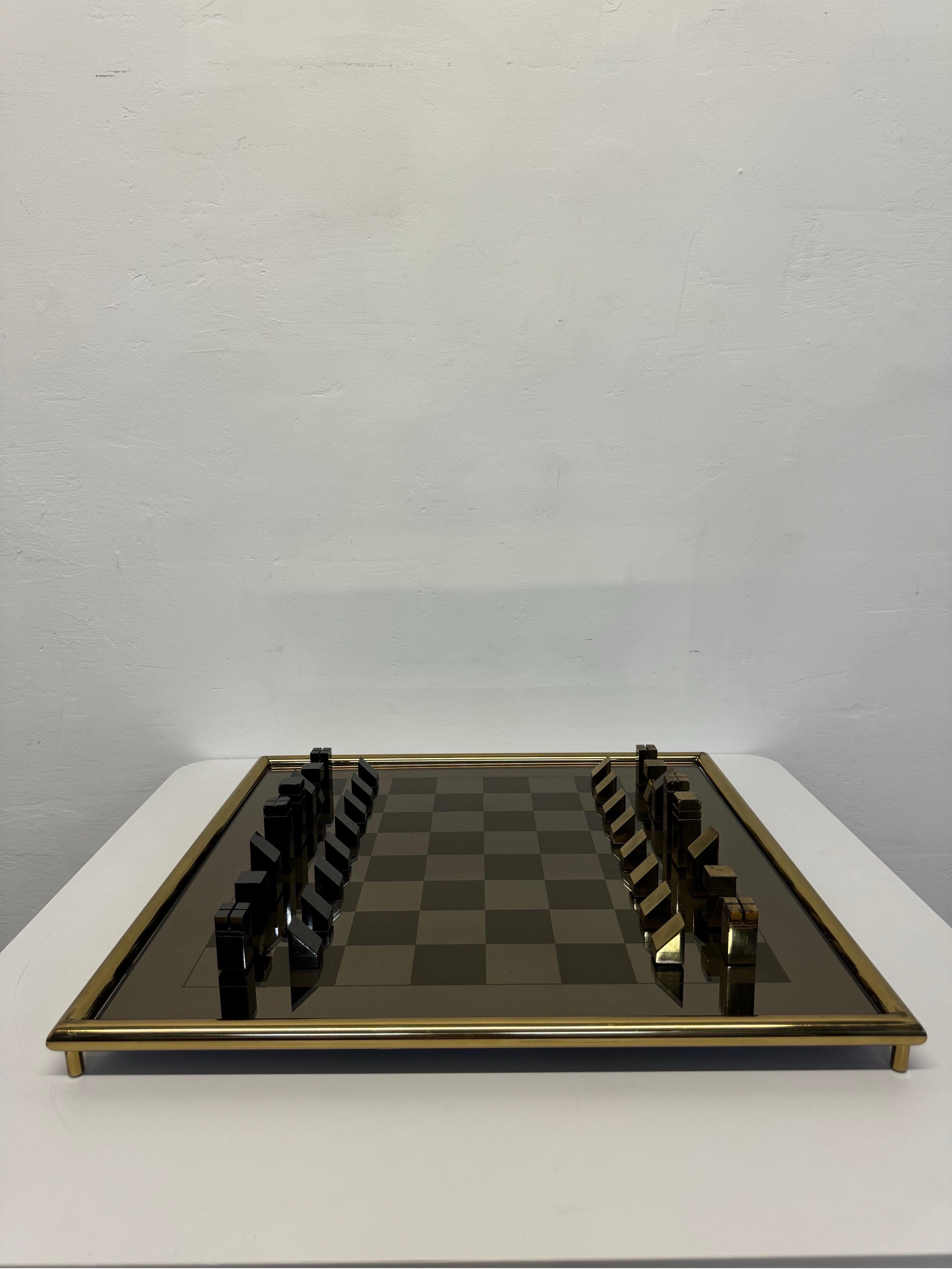 Mid-Century modern chess set with brass and gunmetal pieces on a mirrored glass board.  The glass playing board is inset in a raised brass frame.