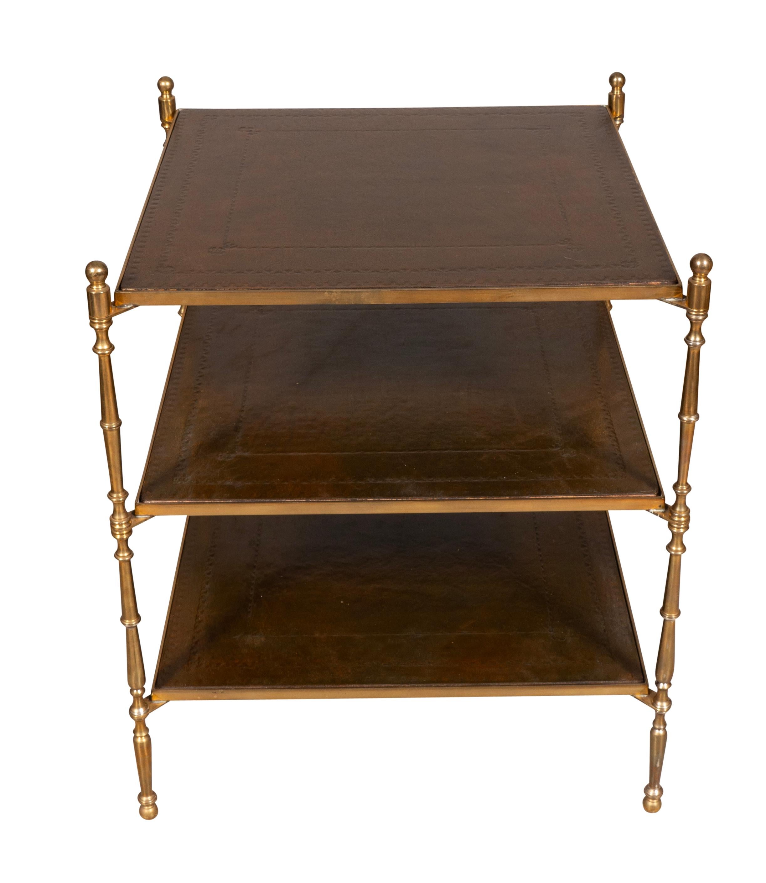 Three  brass framed square brown leather shelves with turned brass supports and legs.