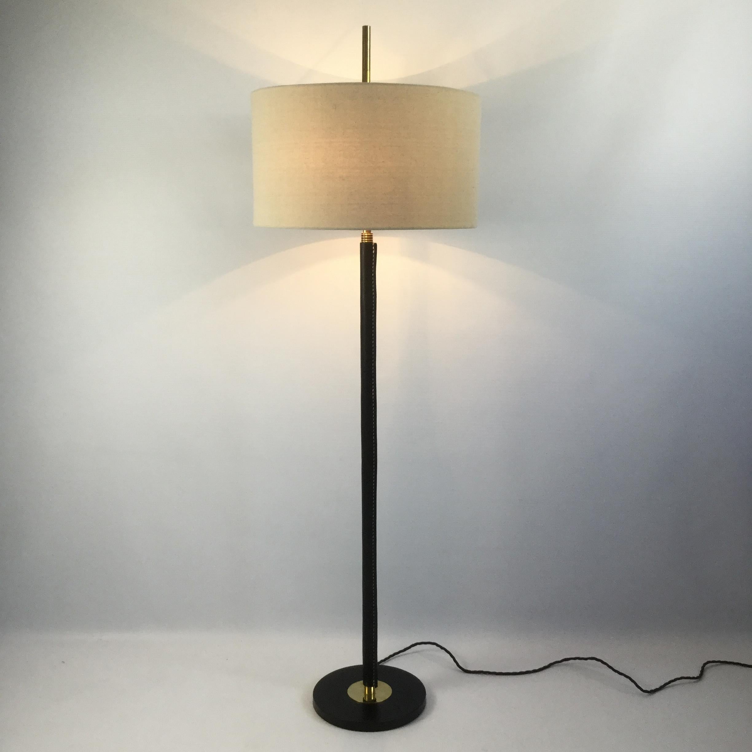 1950s extendable floor lamp in brass in a manner of Jacques Adnet with leather-wrapped finish redone by a professional saddler using a black full-grain leather.
New beige linen lampshade, rewired with insulating fabric cable, double switch.
