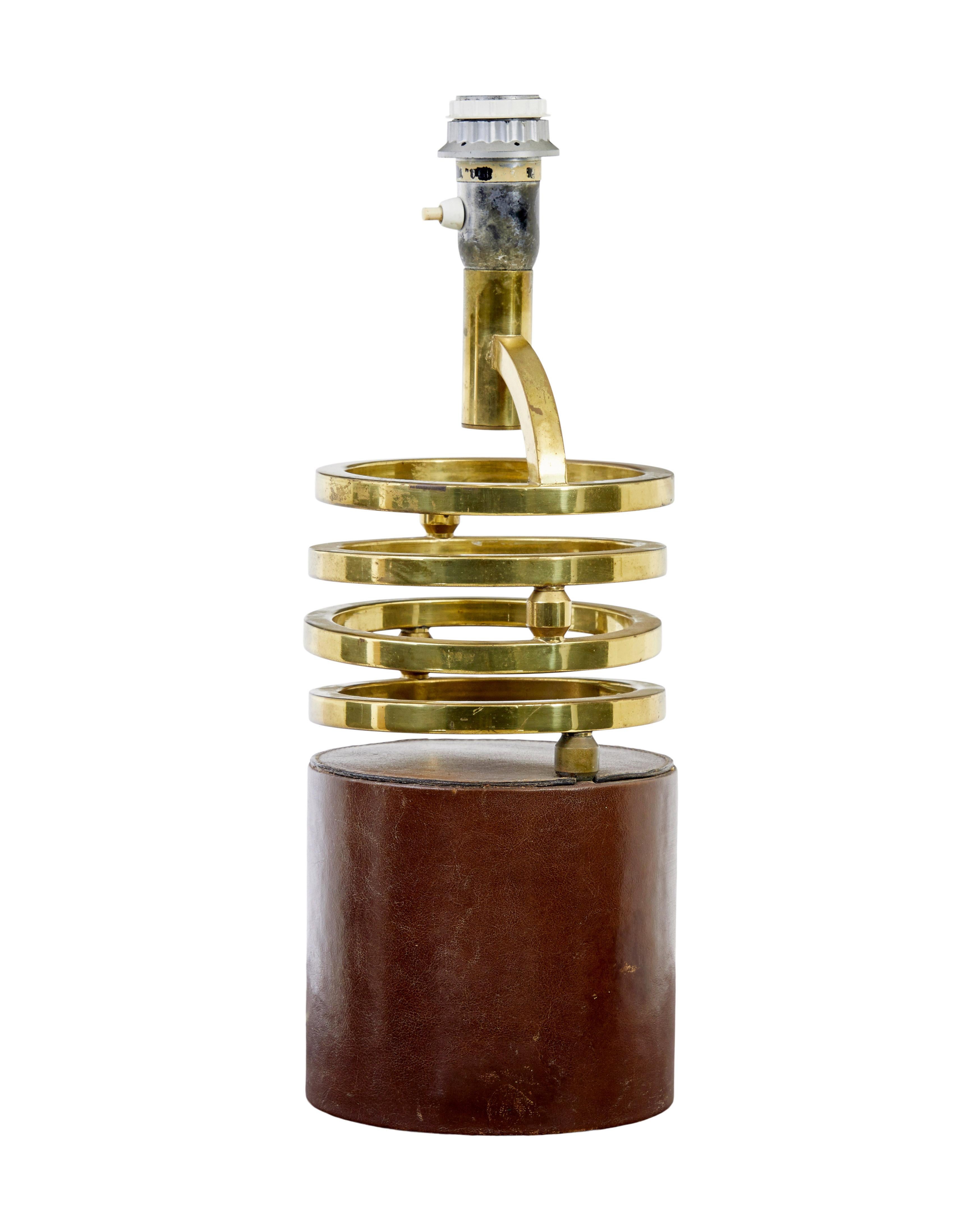 Lampe de table oscillante en laiton et cuir circa 1960.

Base lestée en cuir marron avec 4 anneaux en laiton reliés entre eux qui peuvent se déplacer dans différentes positions, ce qui en fait une bonne alternative à l'Anglepoise. Quelques marques