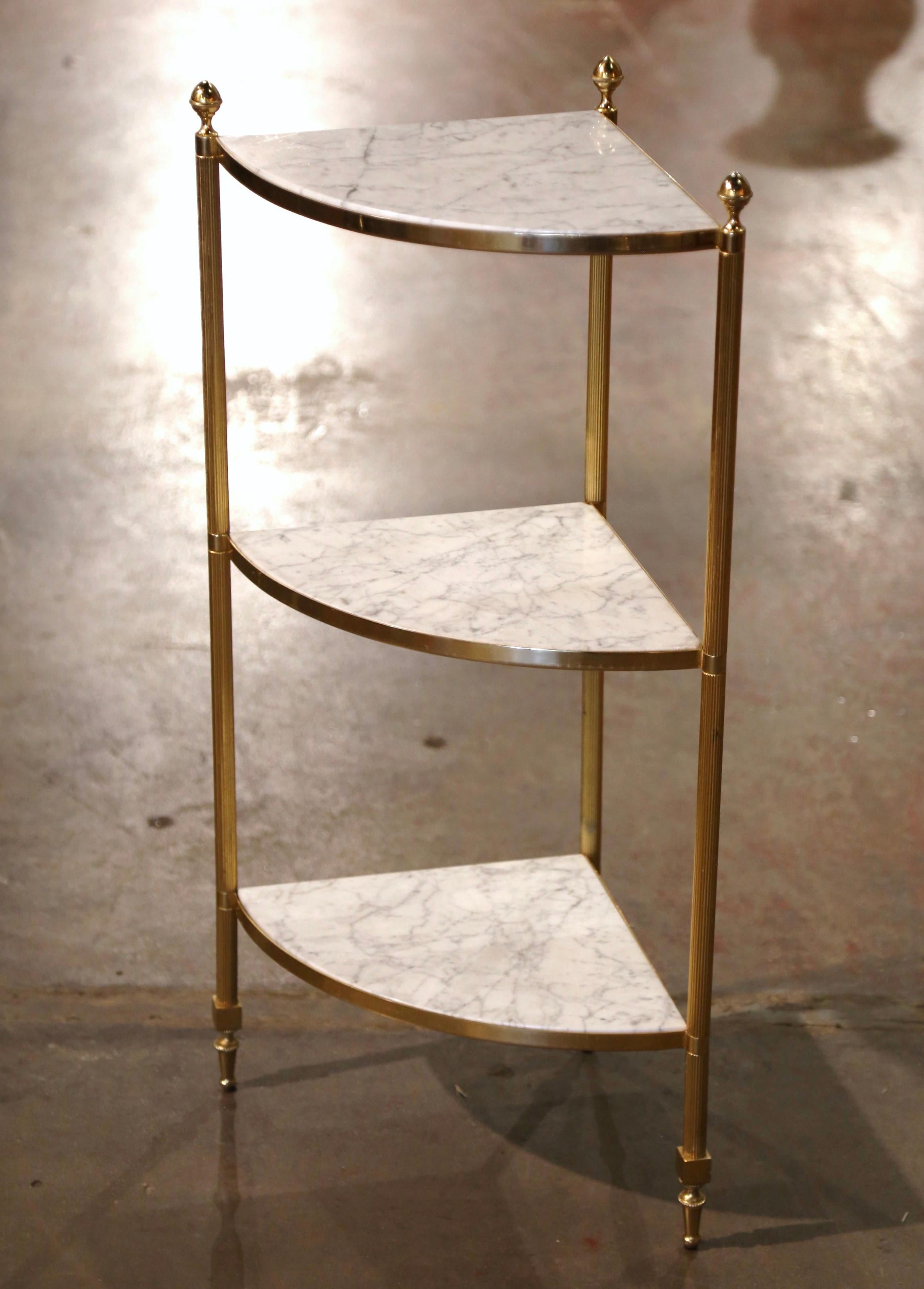 Decorate a corner of a living room or powder room with this elegant brass and marble corner shelf. Created in Paris, France, circa 1950 the clean line frame is made of polished brass; it features three round  fluted legs ending with tapered feet,