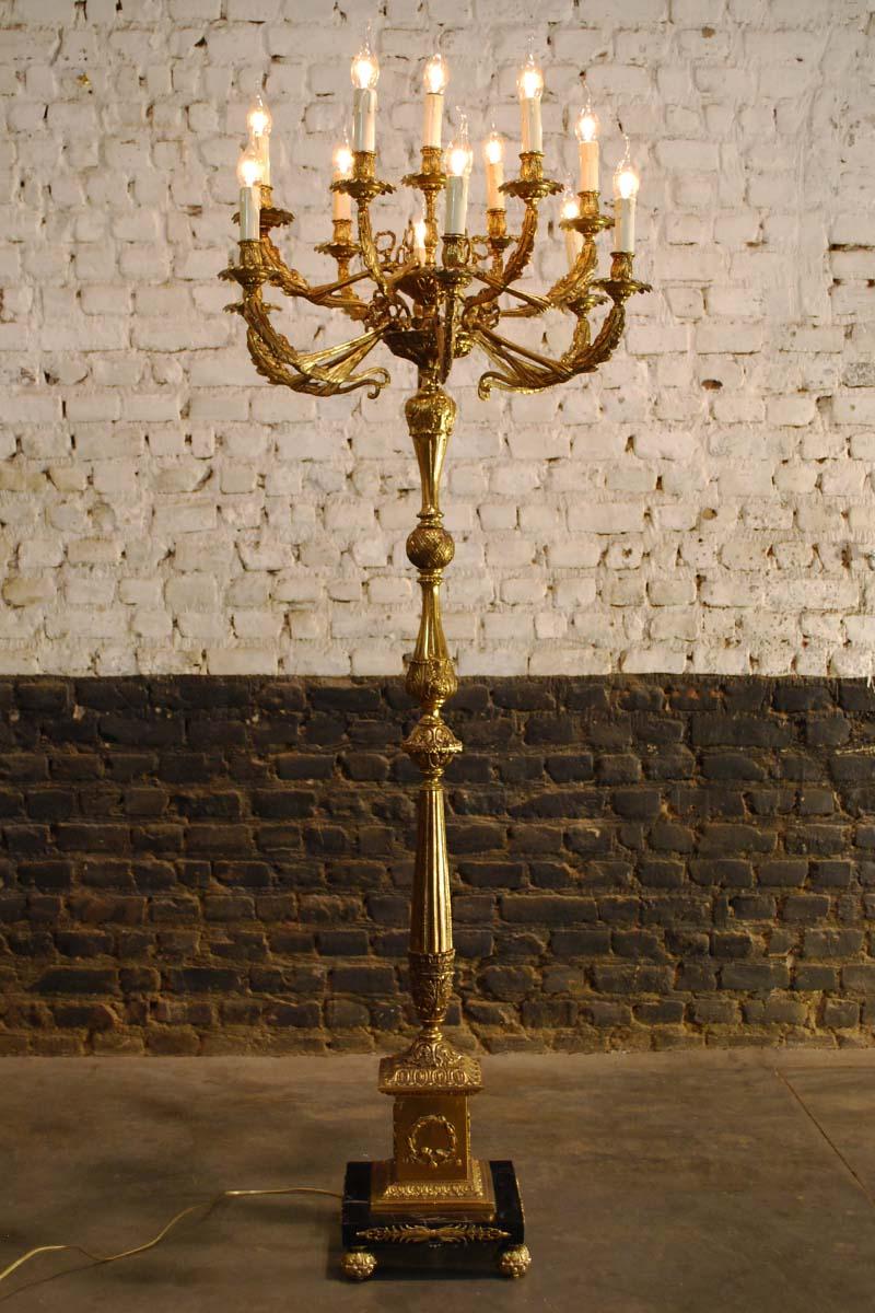 A beautiful French midcentury brass candelabra with black marble base.
It is made in France in the 1950s in Regency style. Its casted brass arms and column depict exotic and floral themes such as pineapple, cloth, and leaves. The candelabra
