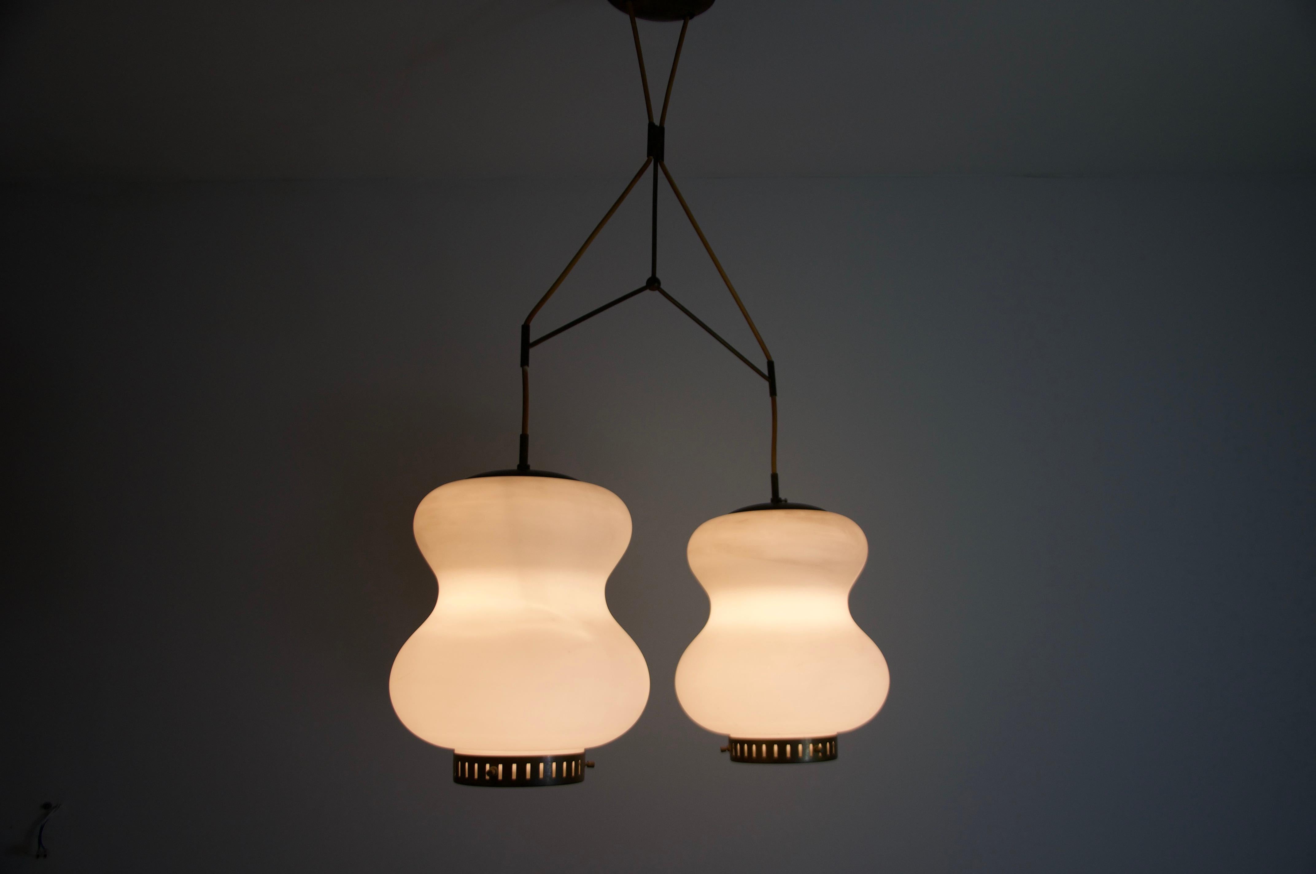 Cette lampe suspendue exquise, conçue par Stilnovo dans les années 1960, est un exemple remarquable du design moderne italien du milieu du siècle dernier. Fabriqué en laiton de haute qualité et en verre opalin, il équilibre parfaitement l'élégance