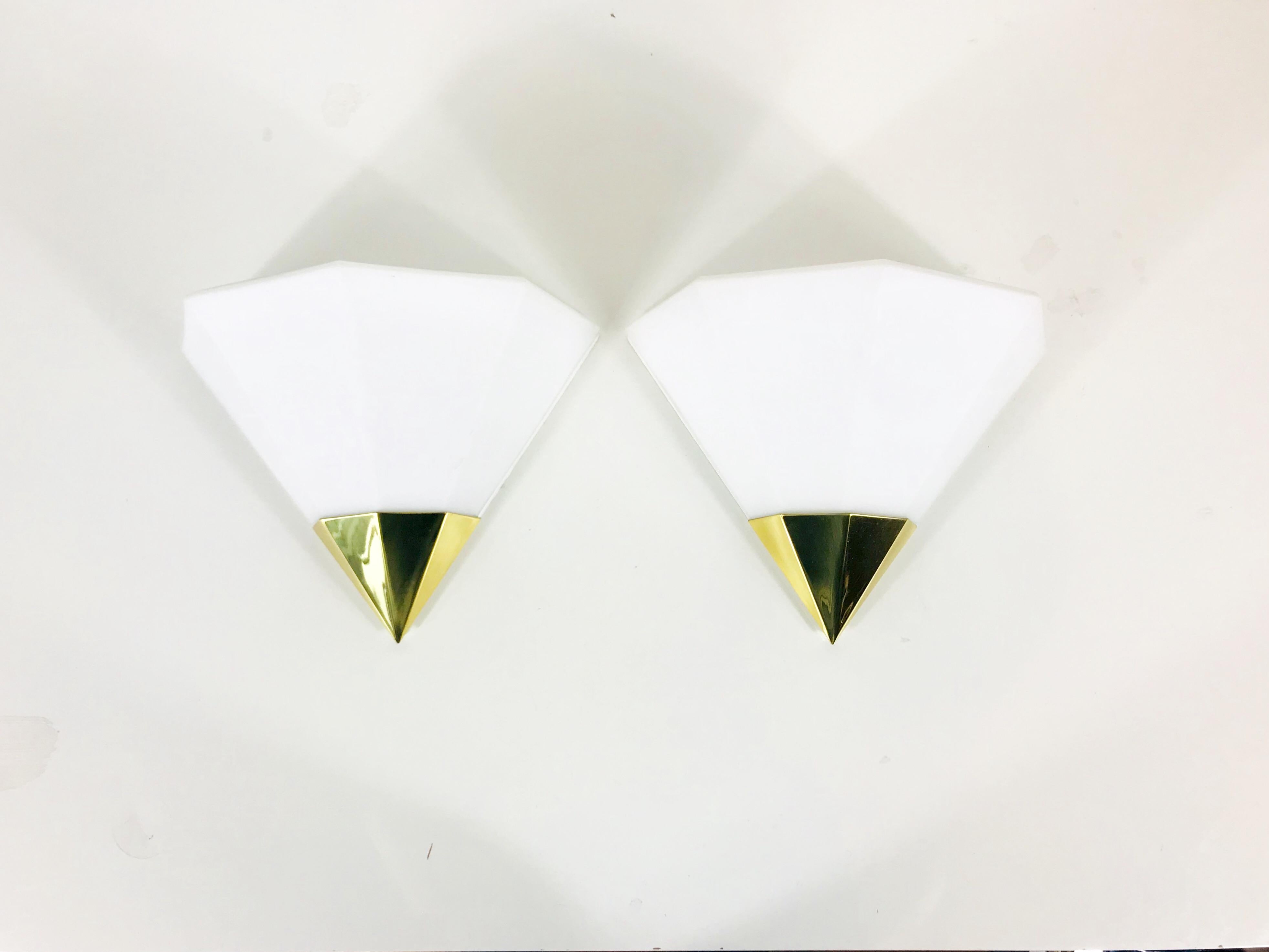 Ein schönes Paar Mid-Century Modern Wandlampen von Glashütte Limburg, hergestellt in Deutschland in den 1970er Jahren. Sie haben eine schöne Dreiecksform und sind aus Messing und Opalglas gefertigt. Die Rückseite ist aus weißem Metall.

Die
