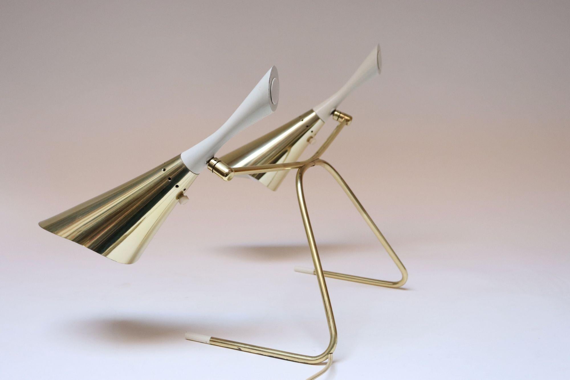 Elegant table lamp featuring two adjustable shades in brass with white painted metal finals supported by a sculptural brass frame with white cylindrical metal feet attributed to Laurel (ca. 1950s, USA).
Very good, vintage condition with light