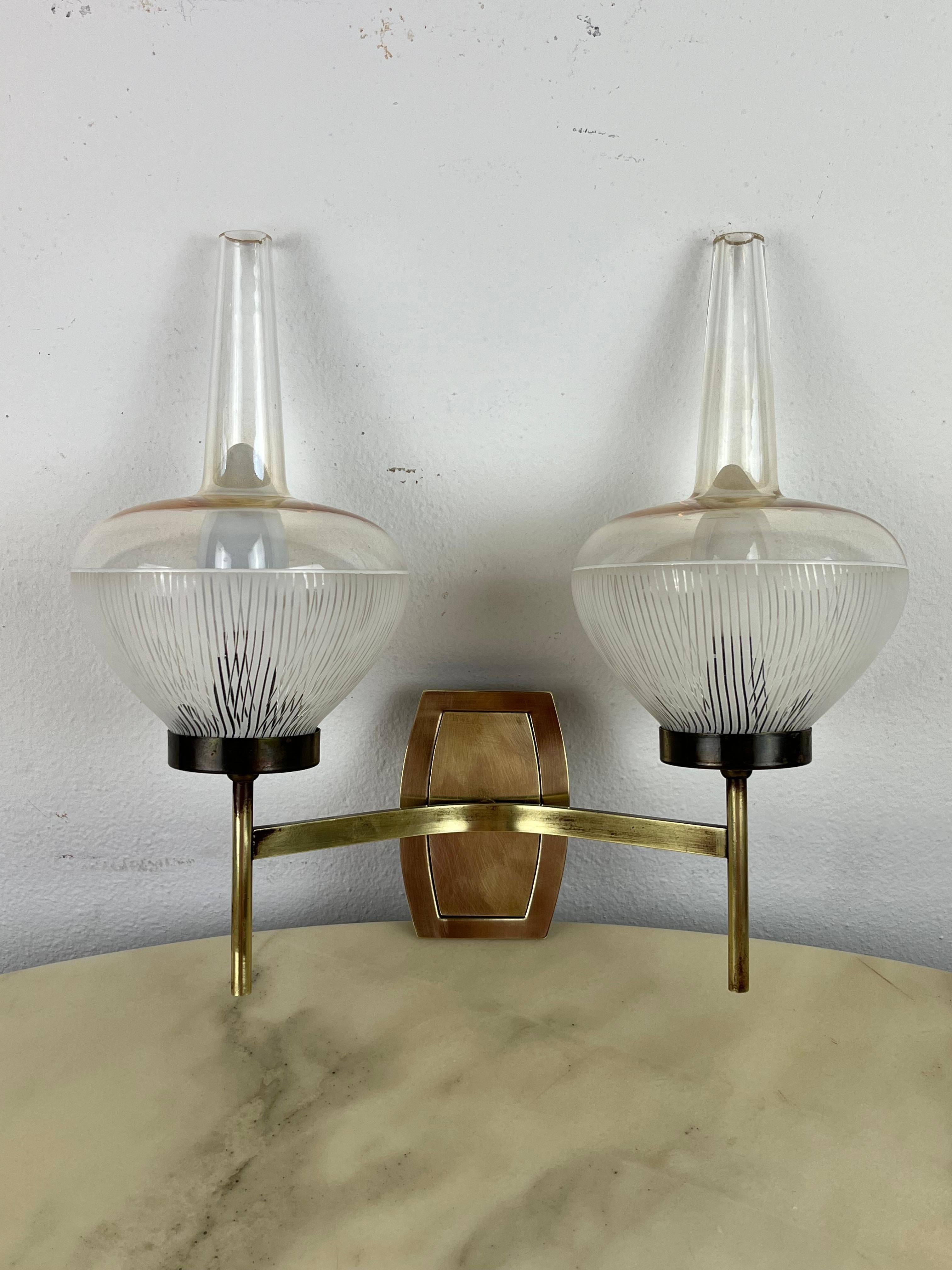 Mid-Century brass and ribbed glass wall light, Italian design from the 1960s.
Two E14 lamps, intact and working, brass and aluminum structure, ribbed glass bowls. Good condition, small signs of aging.