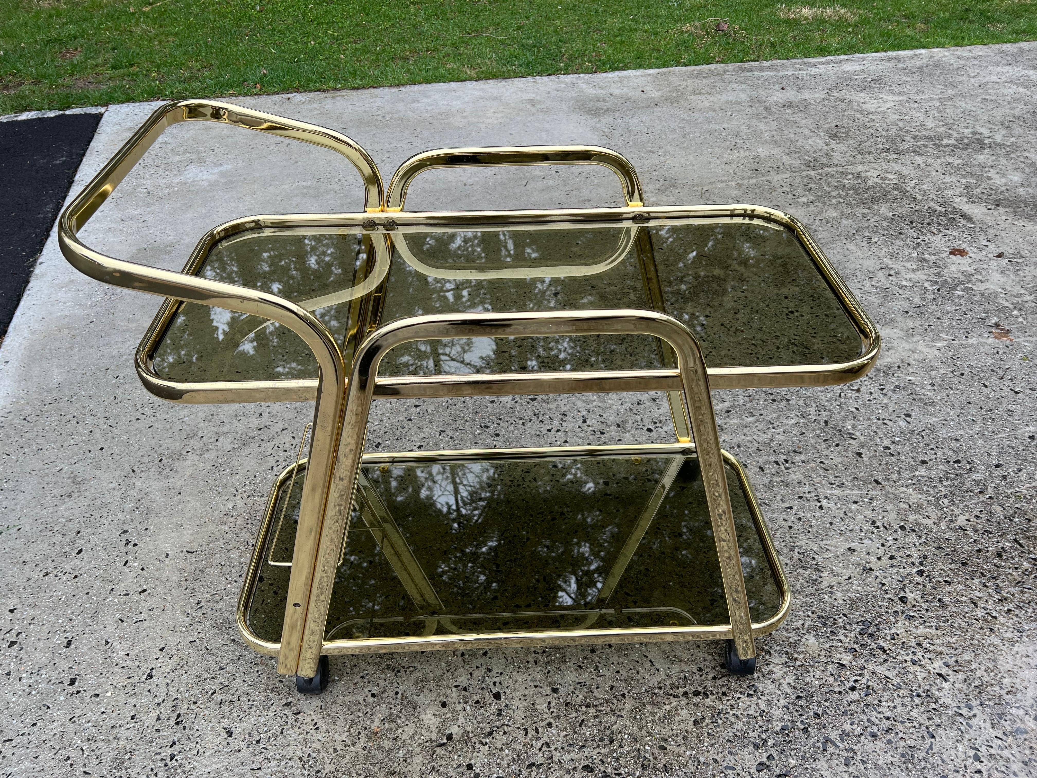 Mid-Century brass and smoked glass bar table/cart on wheels. Sleek and sexy Italian styling most likely attributed to Morex. This size cart is bigger than most bar carts and very sturdy.
 