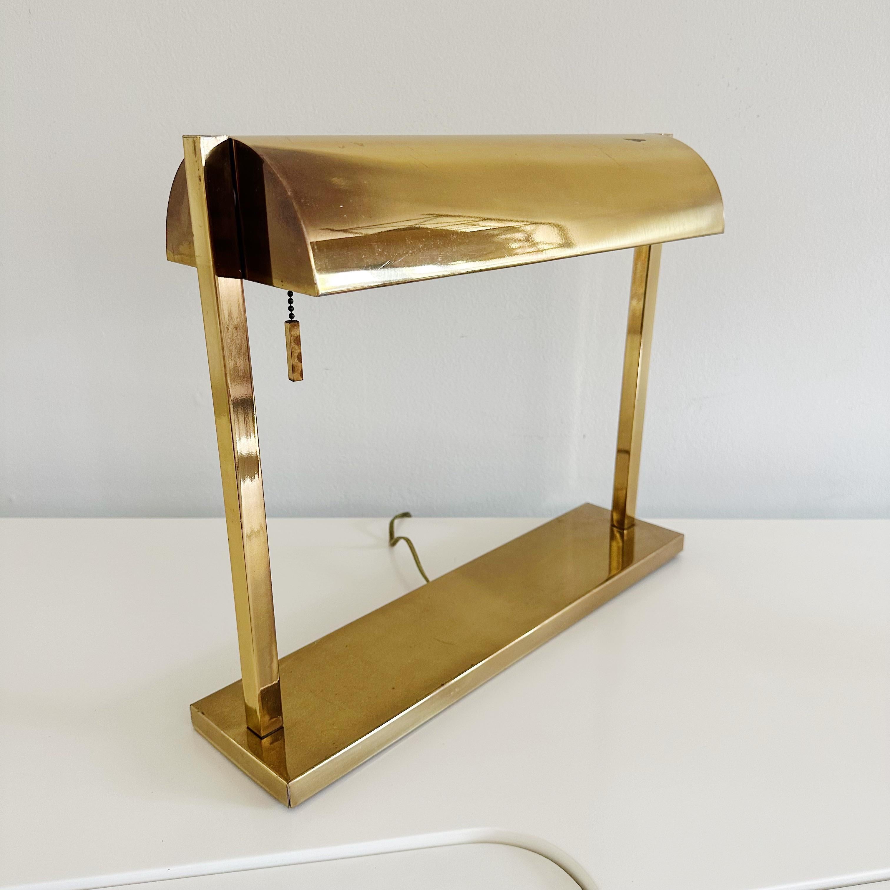 Mid Century Brass Bankers Desk Lamp

Mid 20th century bankers desk lamp in brass with the interior of the adjustable shade being in white enamel, unsigned original wiring