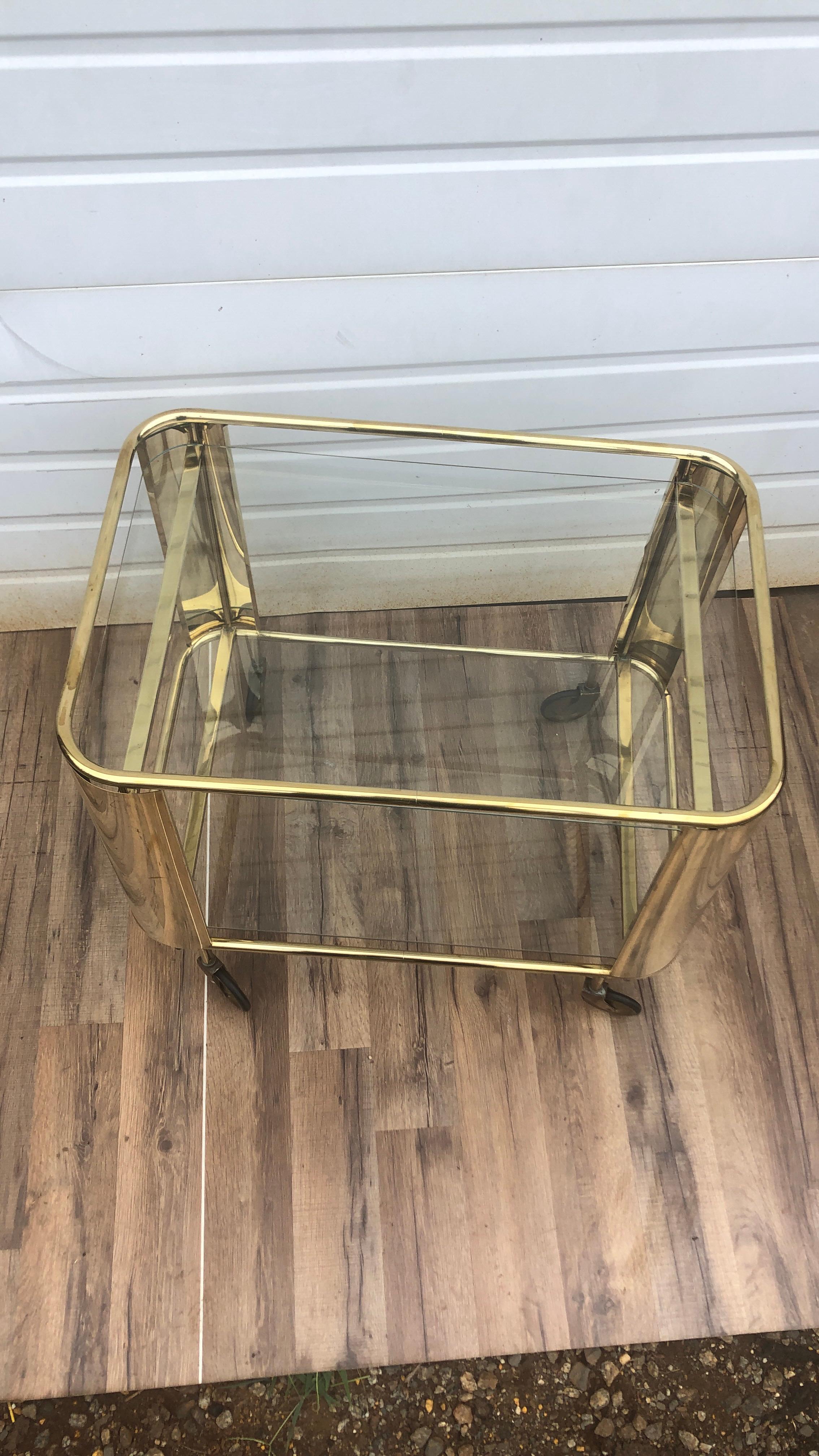 Italian two-tiered rolling brass bar cart. The rectangular cart is framed with four curved brass panels. The size makes this ideal as a side table or bar cart.

Please reach out to us for competitive shipping rates.